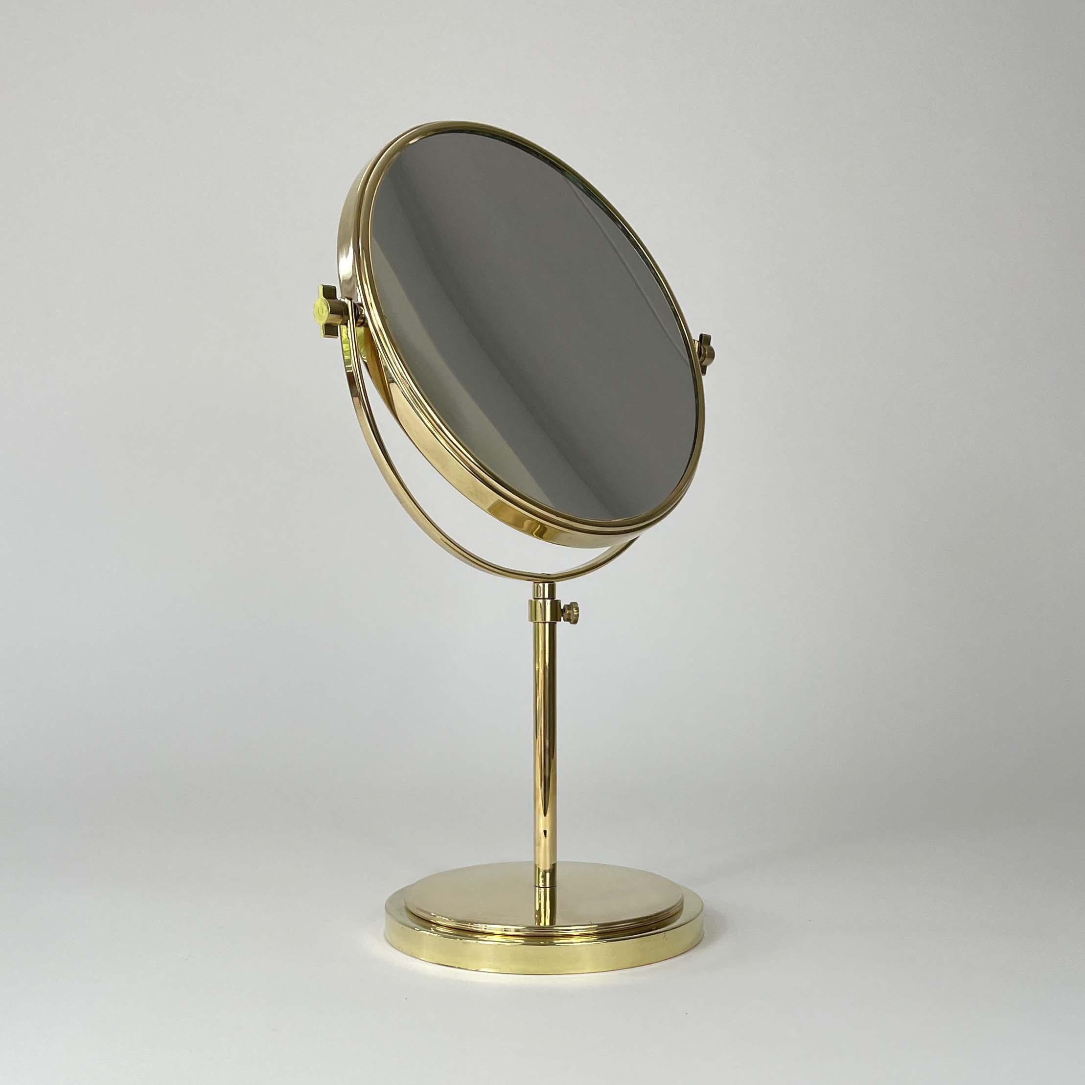 This height adjustable vanity or shaving mirror was designed and manufactured in Sweden in the 1940s to 1950s. It features a double sided brass framed mirror with brass base. 

This beautiful piece is fully adjustable and the mirror is magnified on