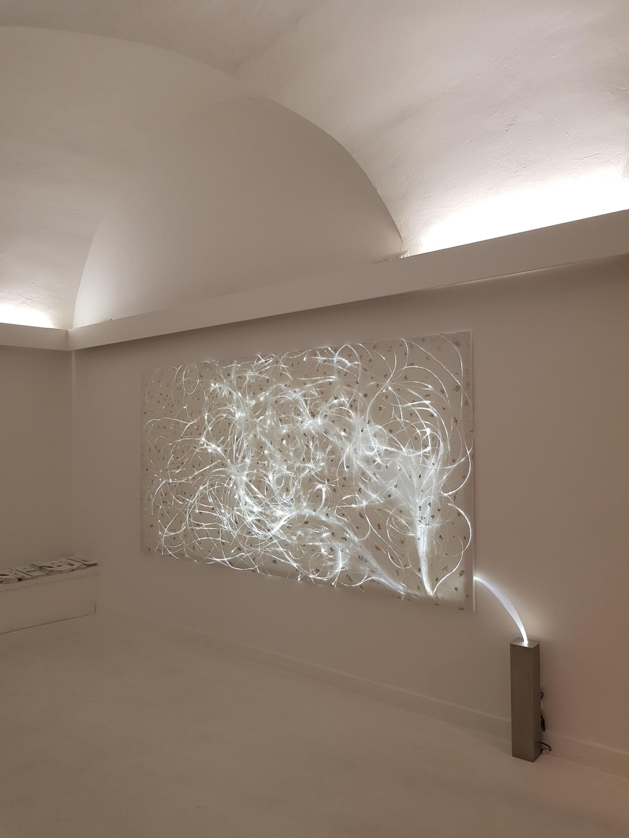 In the delicate light installation LIGHT\TRACE No. 1, fibre optics are embedded in white, handmade hand-made paper and gently trace their tracks over the entire surface. The transparent, fine fibre optics subtly emit their light and the viewer's