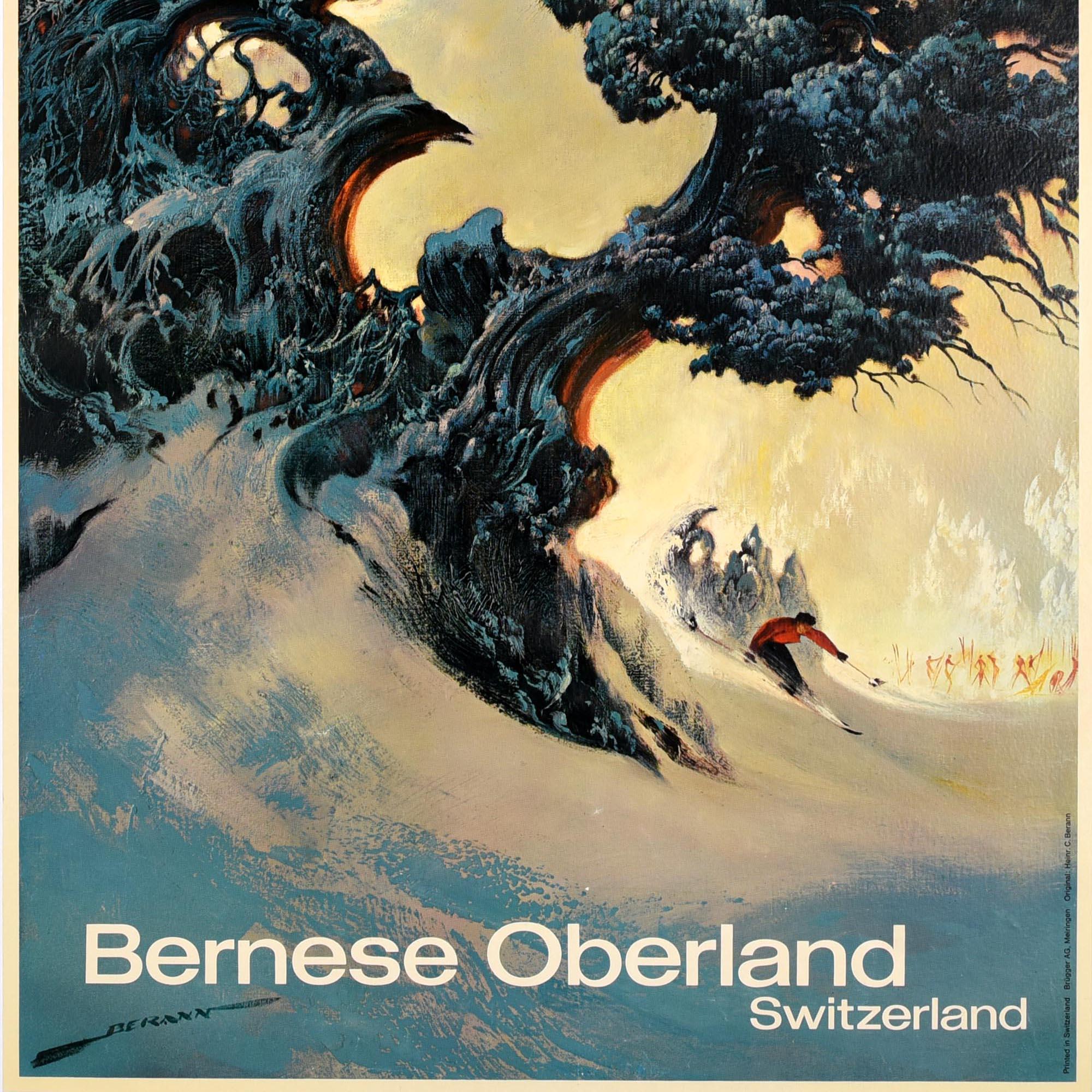 Original vintage ski and winter sport travel poster for the Bernese Oberland Switzerland featuring dramatic artwork by Heinrich Berann (1915-1999) depicting a skier skiing at speed behind a dark tree in the snow with figures holding their skis in