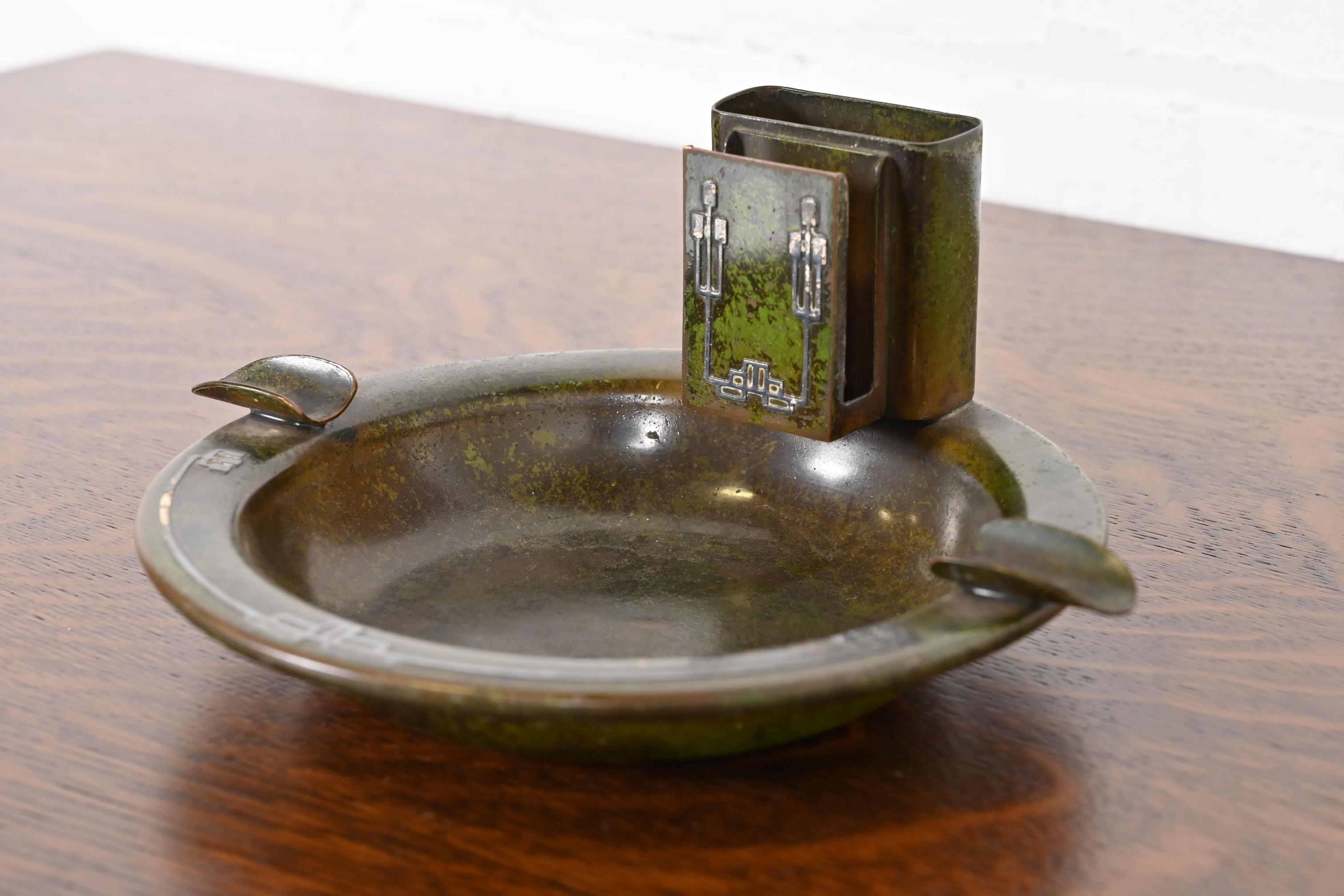 A beautiful Arts & Crafts or Art Deco period sterling silver on bronze ashtray with verdigris green patina

By Heintz Art Metal Shop (signed to the underside)

USA, Early 20th Century

Sterling silver inlay on patinated bronze.

Measures: 9