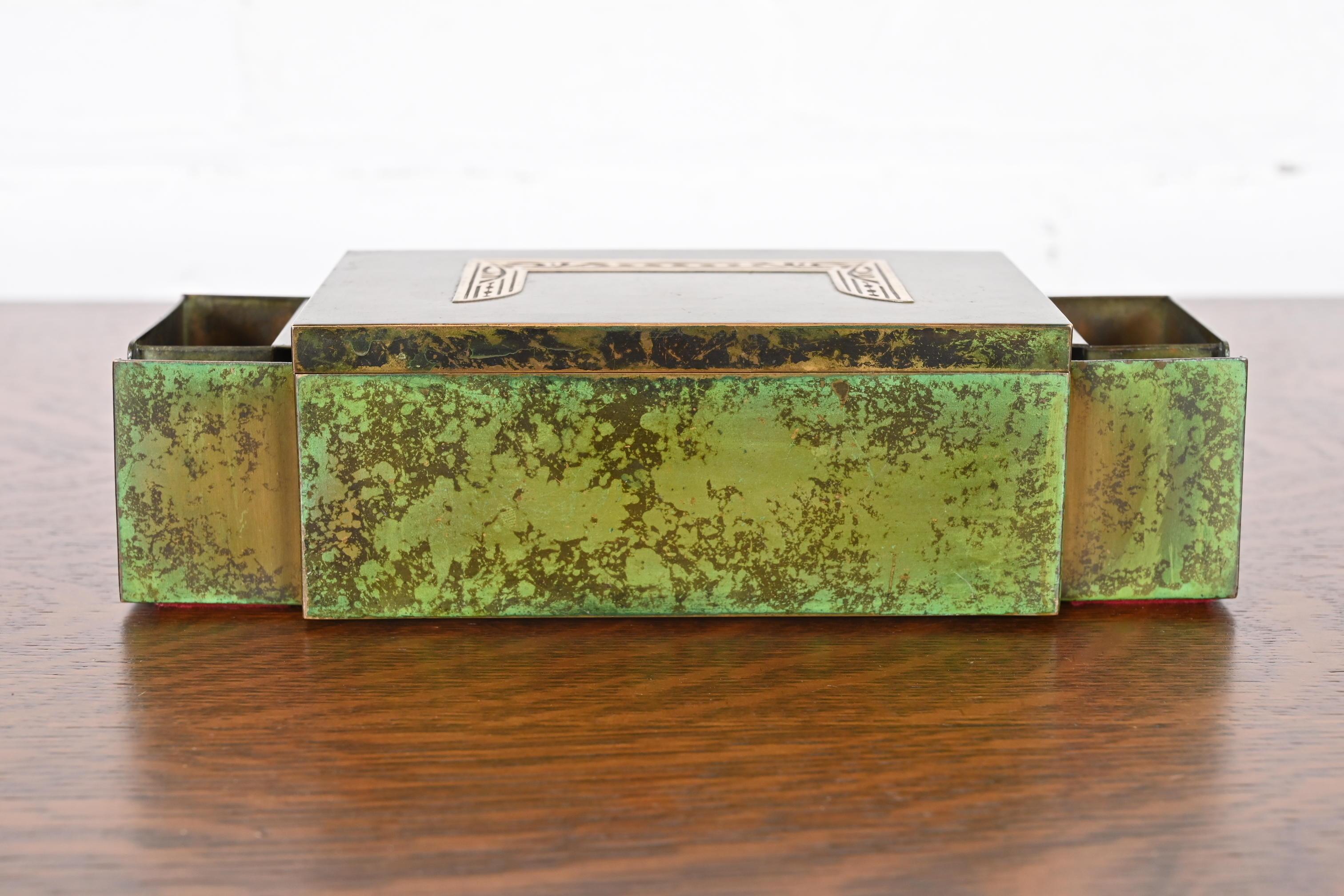 Preciosa caja de puros o humidor de época Arts & Crafts o Art Déco con doble caja de cerillas y soportes para cerillas

Por Heintz Art Metal Shop

EE.UU., principios del siglo XX

Plata de ley sobre bronce patinado, con interior forrado de cedro y