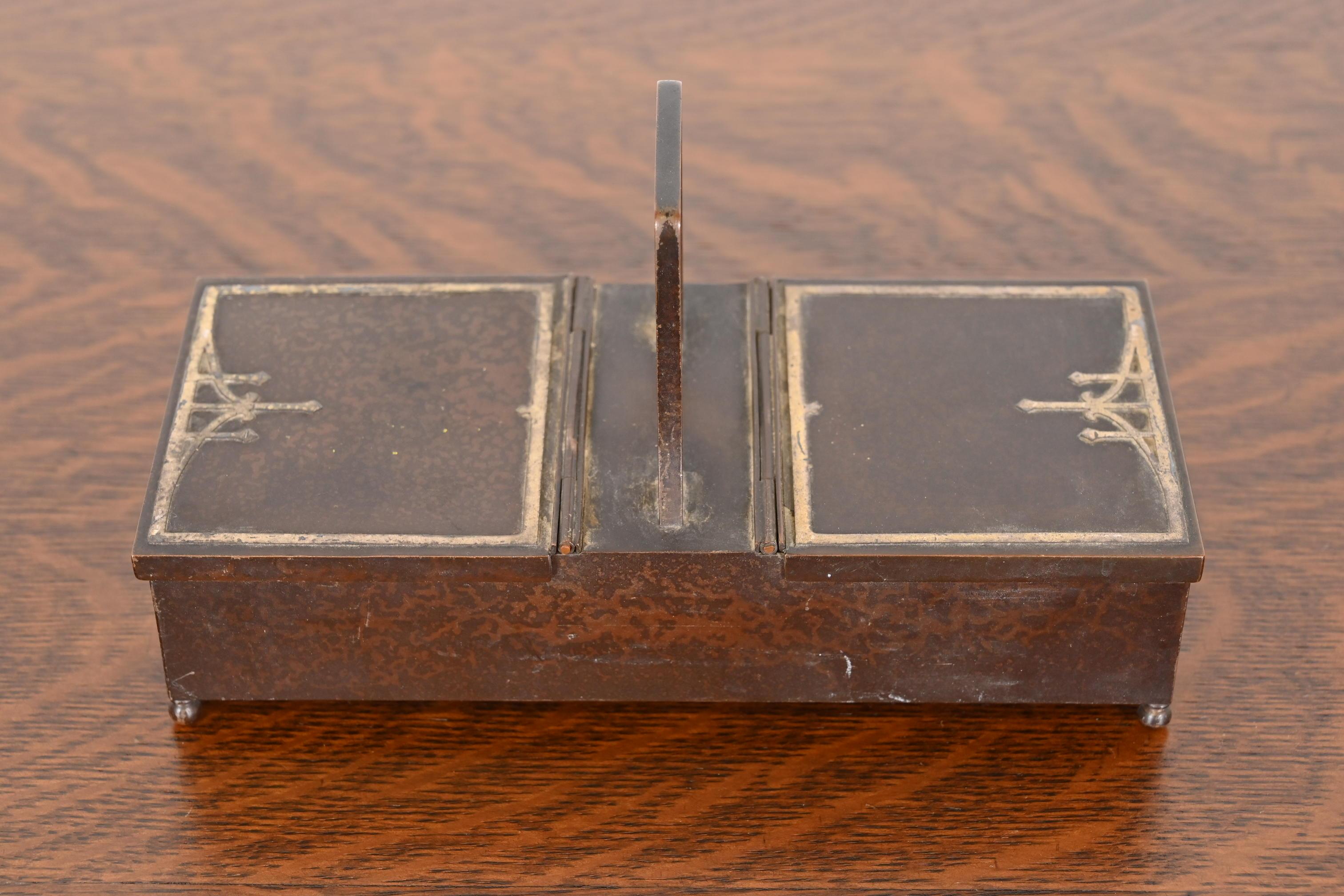 Un magnífico humidor o cigarrera doble de época Arts & Crafts

Por Heintz Art Metal Shop

EE.UU., principios del siglo XX

Plata de ley sobre bronce patinado, con interior forrado de cedro.

Medidas: 8