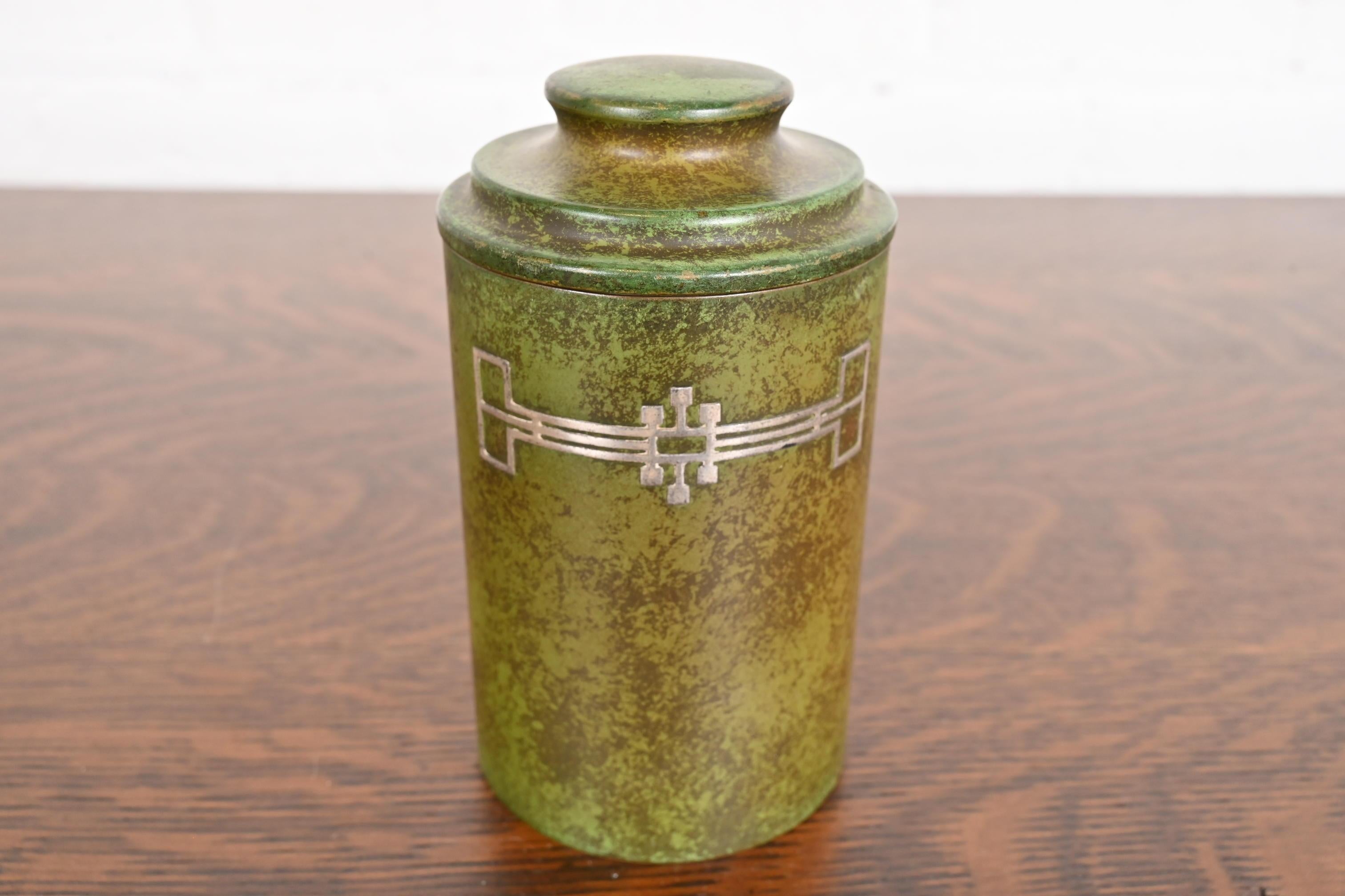 A beautiful Arts & Crafts period sterling silver on bronze lidded canister, tea caddy, or humidor cigar box with verdigris green patina

By Heintz Art Metal Shop

USA, Early 20th Century

Sterling silver inlay on patinated bronze.

Measures: 3.75