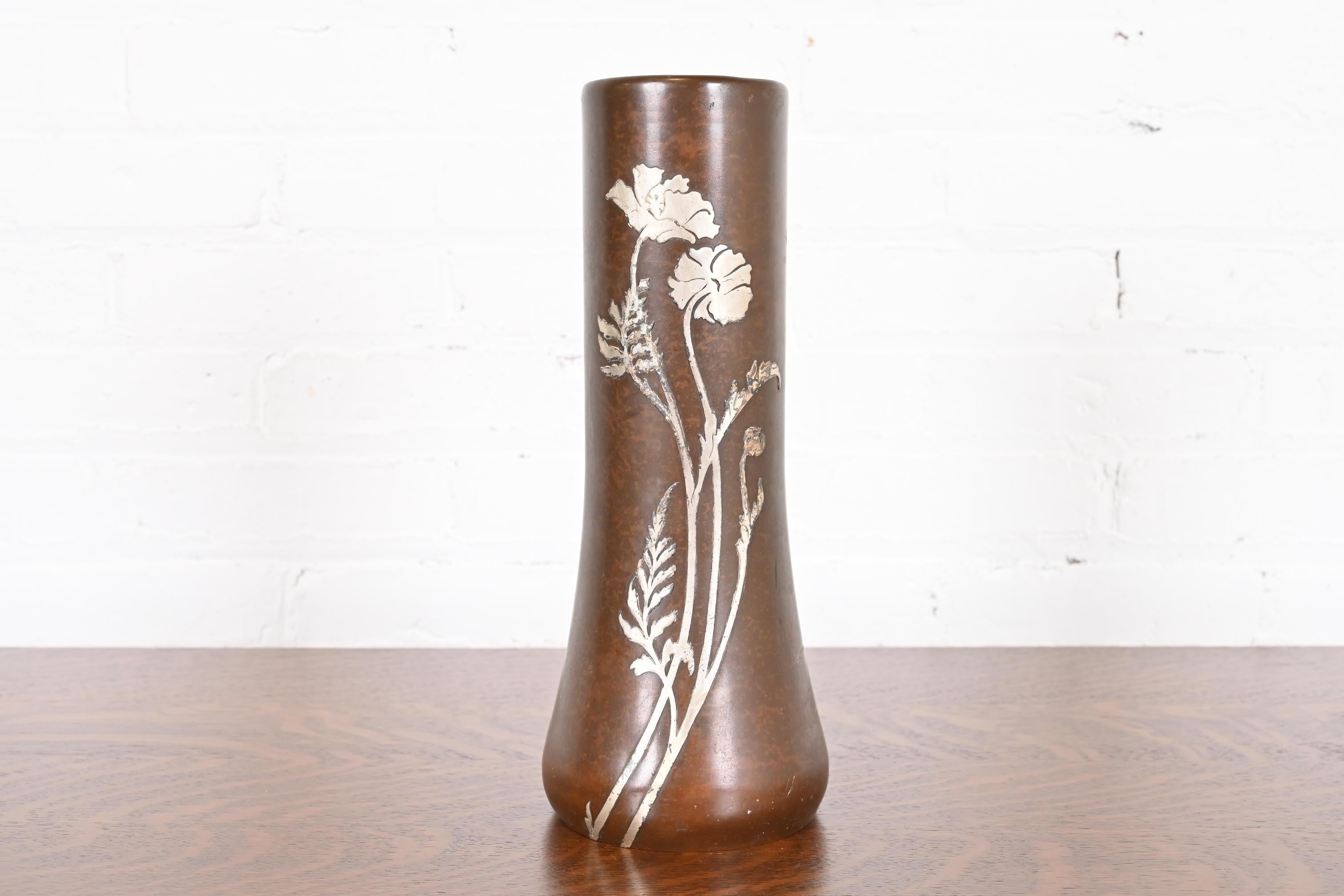 Un bellissimo vaso di grandi dimensioni in argento sterling e bronzo del periodo Arts & Crafts con disegno floreale

Da Heintz Art Metal Shop

Stati Uniti, inizio del XX secolo

Intarsio in argento su bronzo patinato.

Misure: 5