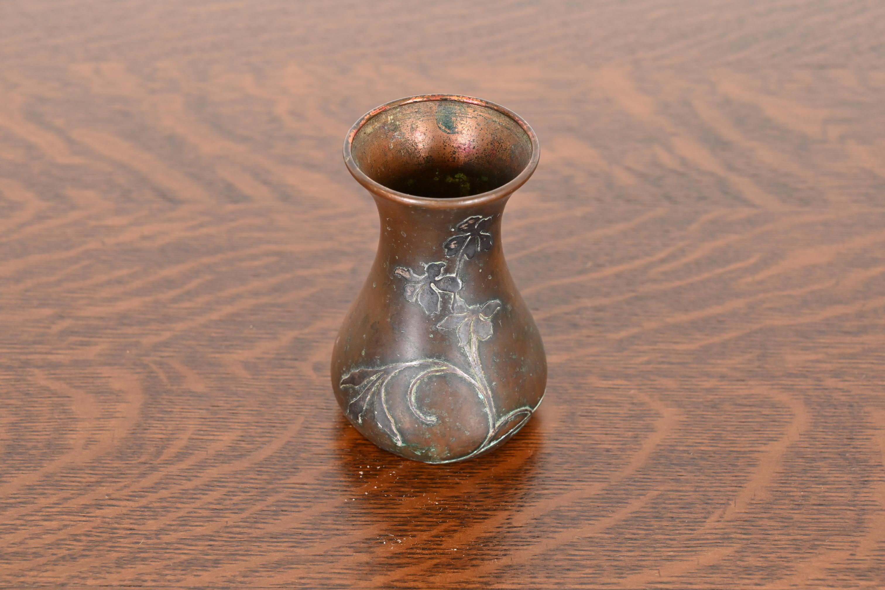 A beautiful Arts & Crafts period sterling silver on bronze petite vase with floral motif

By Heintz Art Metal Shop

USA, Early 20th Century

Sterling silver inlay on patinated bronze.

Measures: 2.75