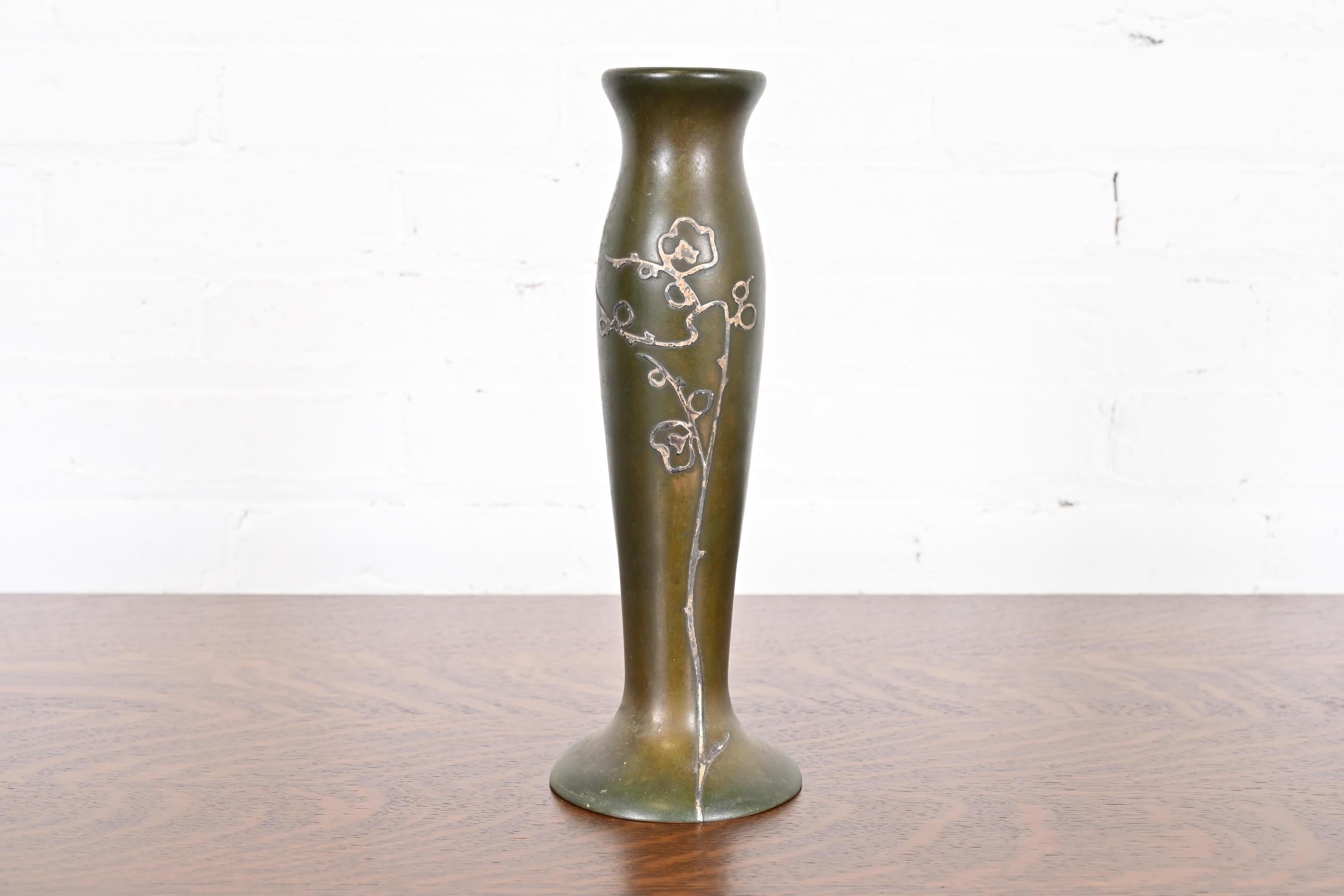 Un bellissimo vaso alto in argento sterling e bronzo del periodo Arts & Crafts con patina verde verdastro e motivo floreale

Da Heintz Art Metal Shop

Stati Uniti, inizio del XX secolo

Intarsio in argento su bronzo patinato.

Misure: 4 