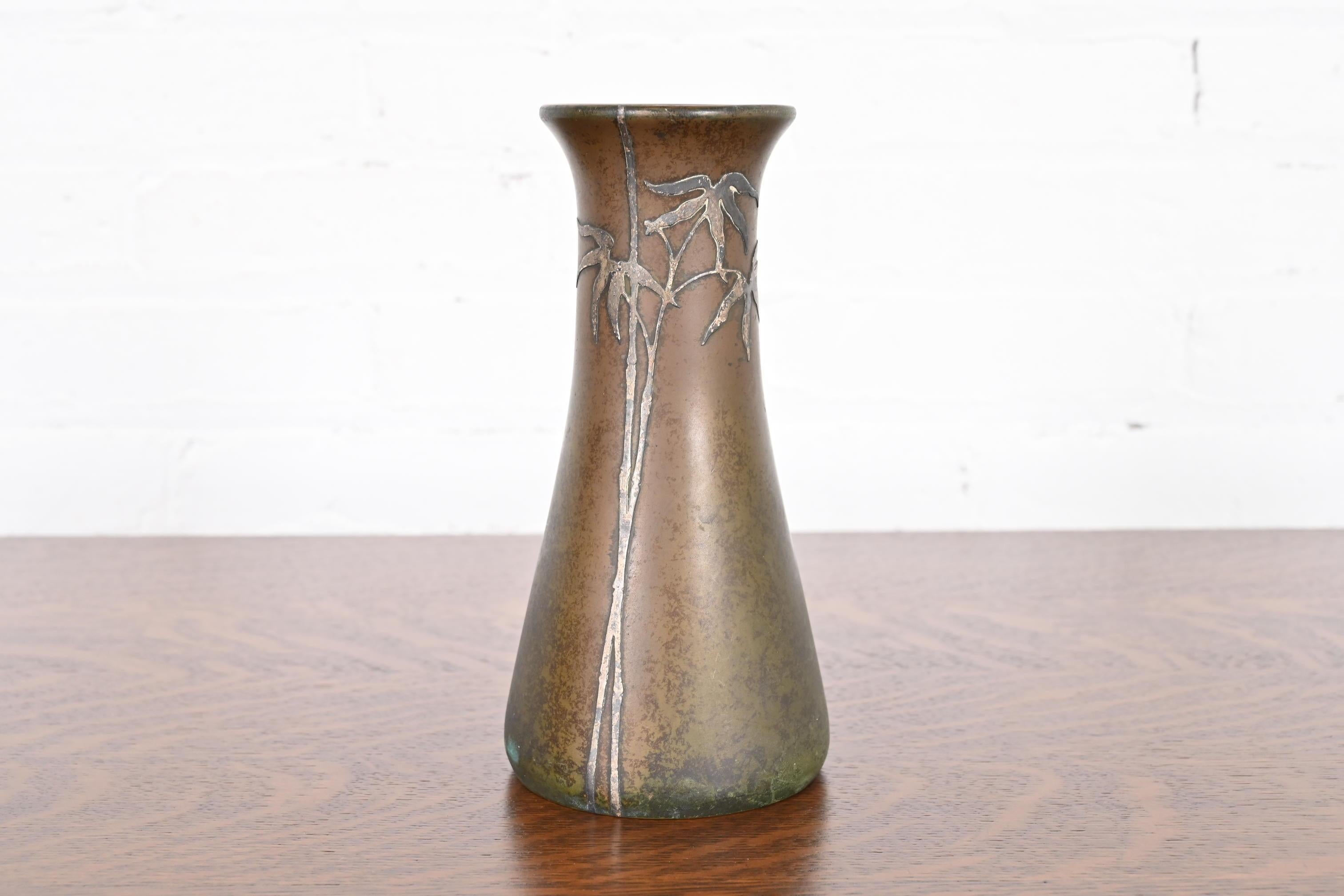 A beautiful Arts & Crafts period sterling silver on bronze vase with floral design

By Heintz Art Metal Shop

USA, Early 20th Century

Sterling silver inlay on patinated bronze.

Measures: 4