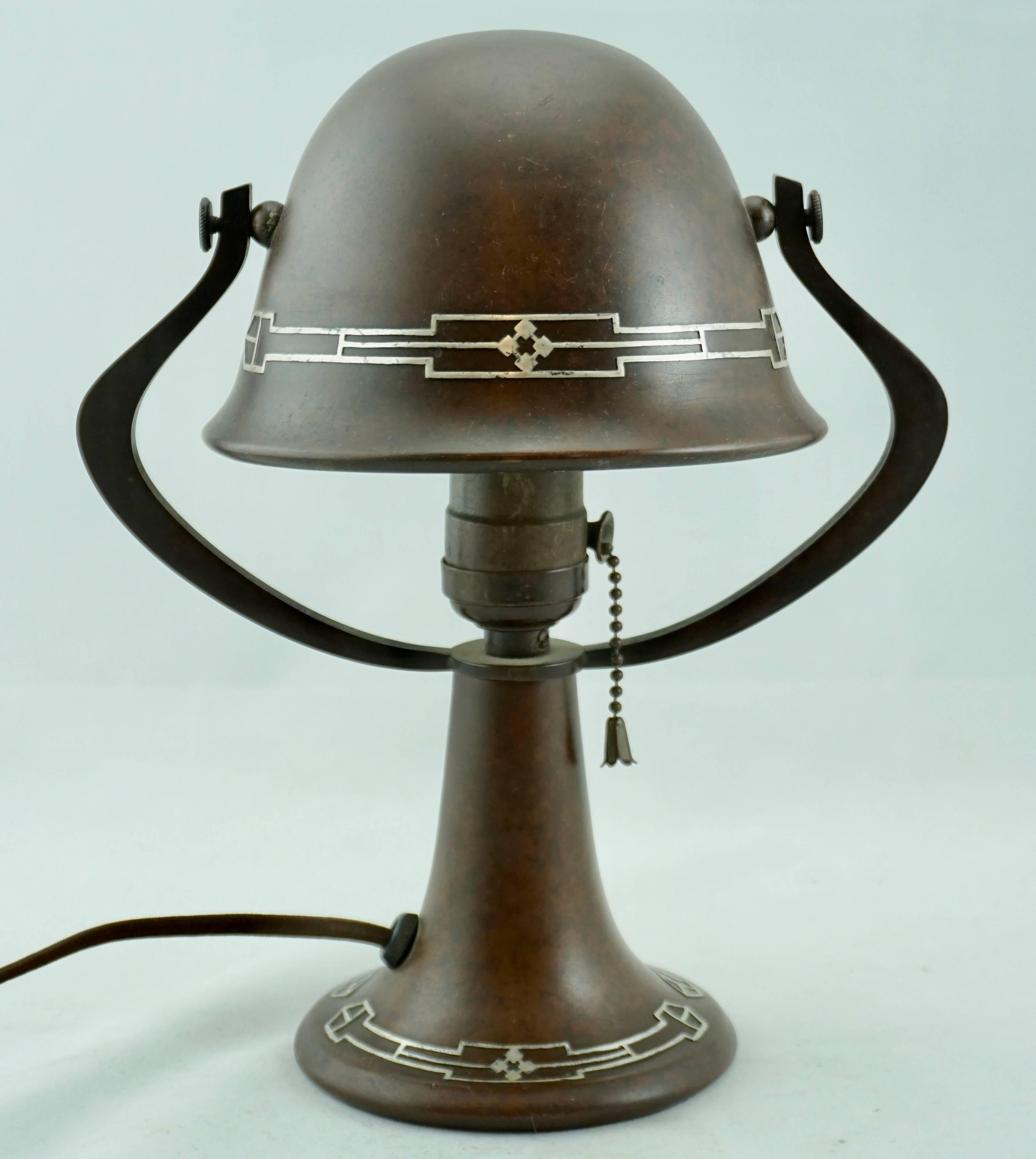 A small Heintz patinated bronze and silver overlay table lamp, circa 1920 Art Nouveau, Art Deco, Arts & Crafts design. Shade and base are made of bronze with silver overlay perfect as a desk or bedside table lamp emitting a beautiful soft glow.