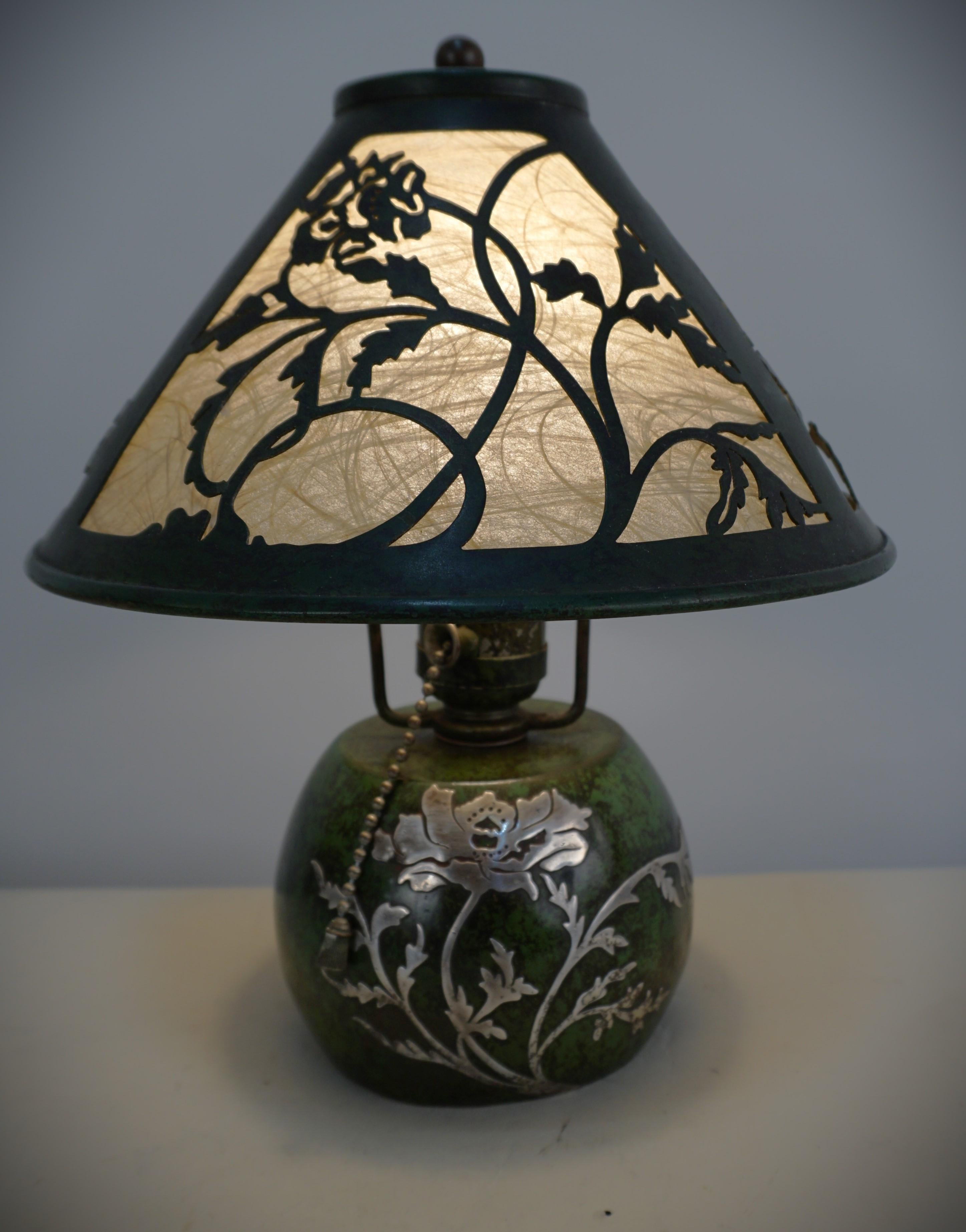 Heintz sterling silver overlay on green textured bronze table lamp with flora cut out design shade and same design silver on base. 
