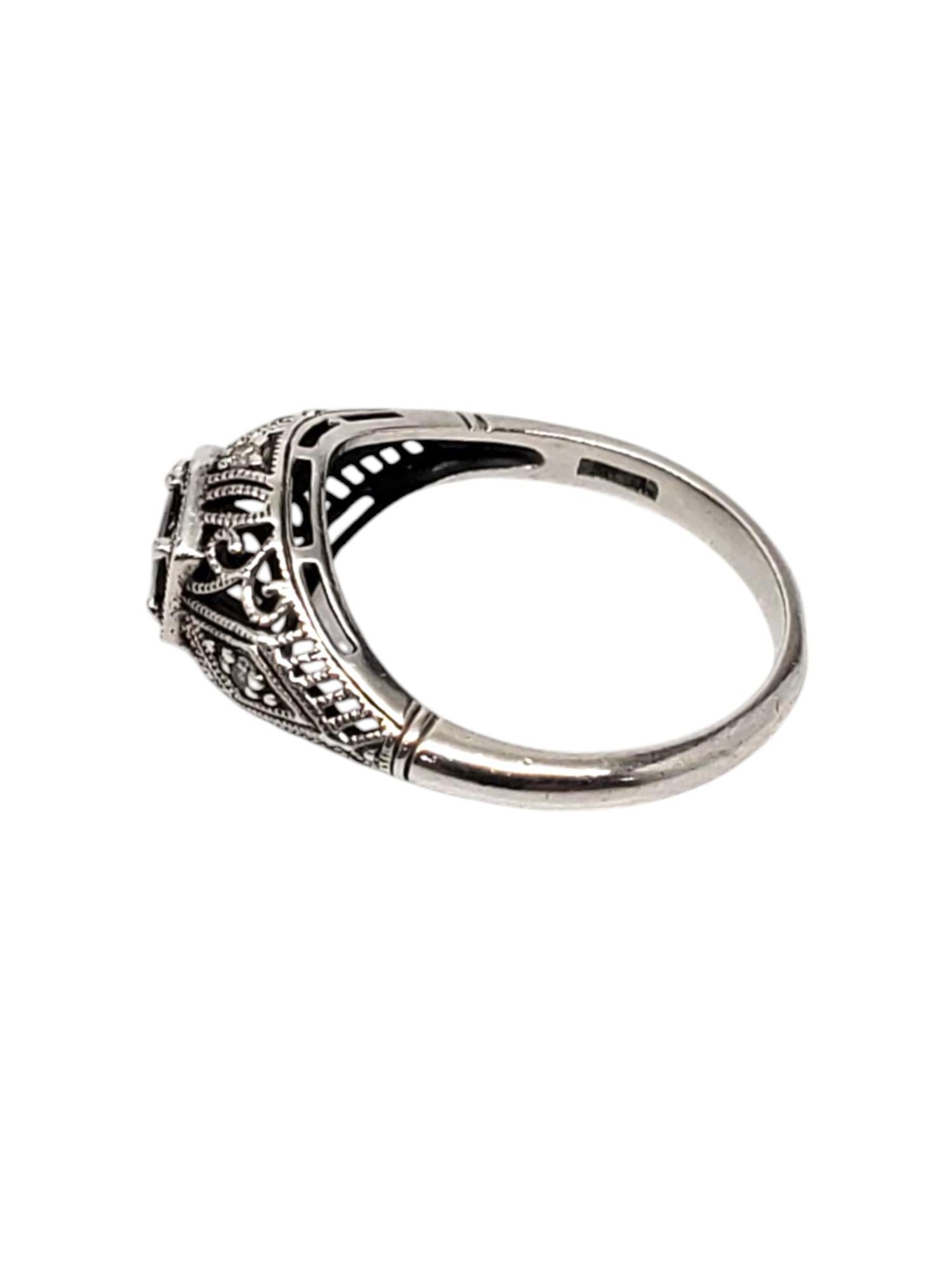 Heirloom 73 Sterling Silver Art Deco Sapphire & Diamond Ring 

This vintage art deco ring features a large round sapphire (5.0 mm) with 4 round diamond accent stones set in a filigree sterling silver design by Heirloom 73.

Shank: 2.14

Size: