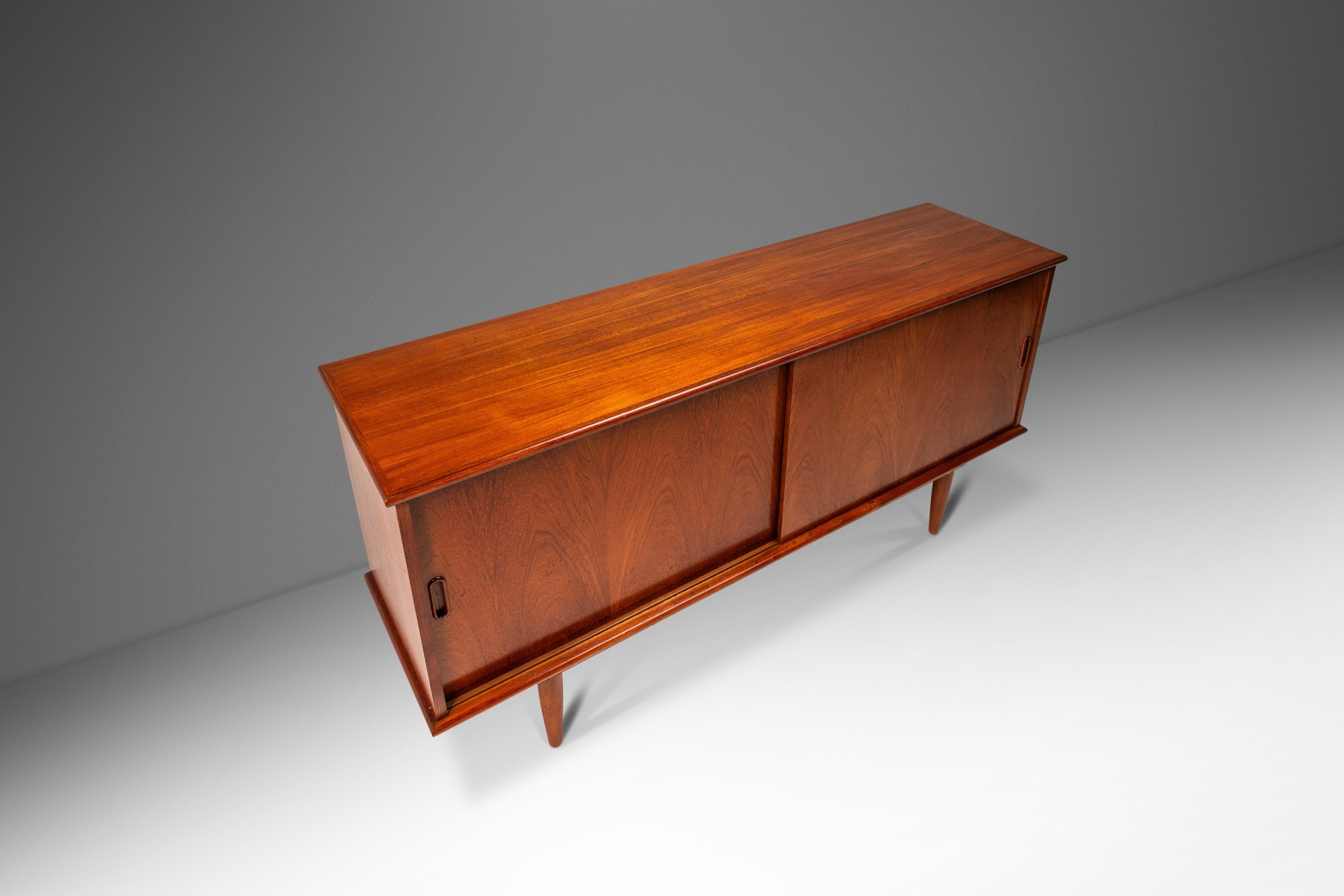 Elevate your living space with this exquisite heirloom cabinet, credenza, buffet, or media center attributed to the renowned designer Arne Vodder. This piece showcases design features consistent with Vodder's celebrated style and is crafted with