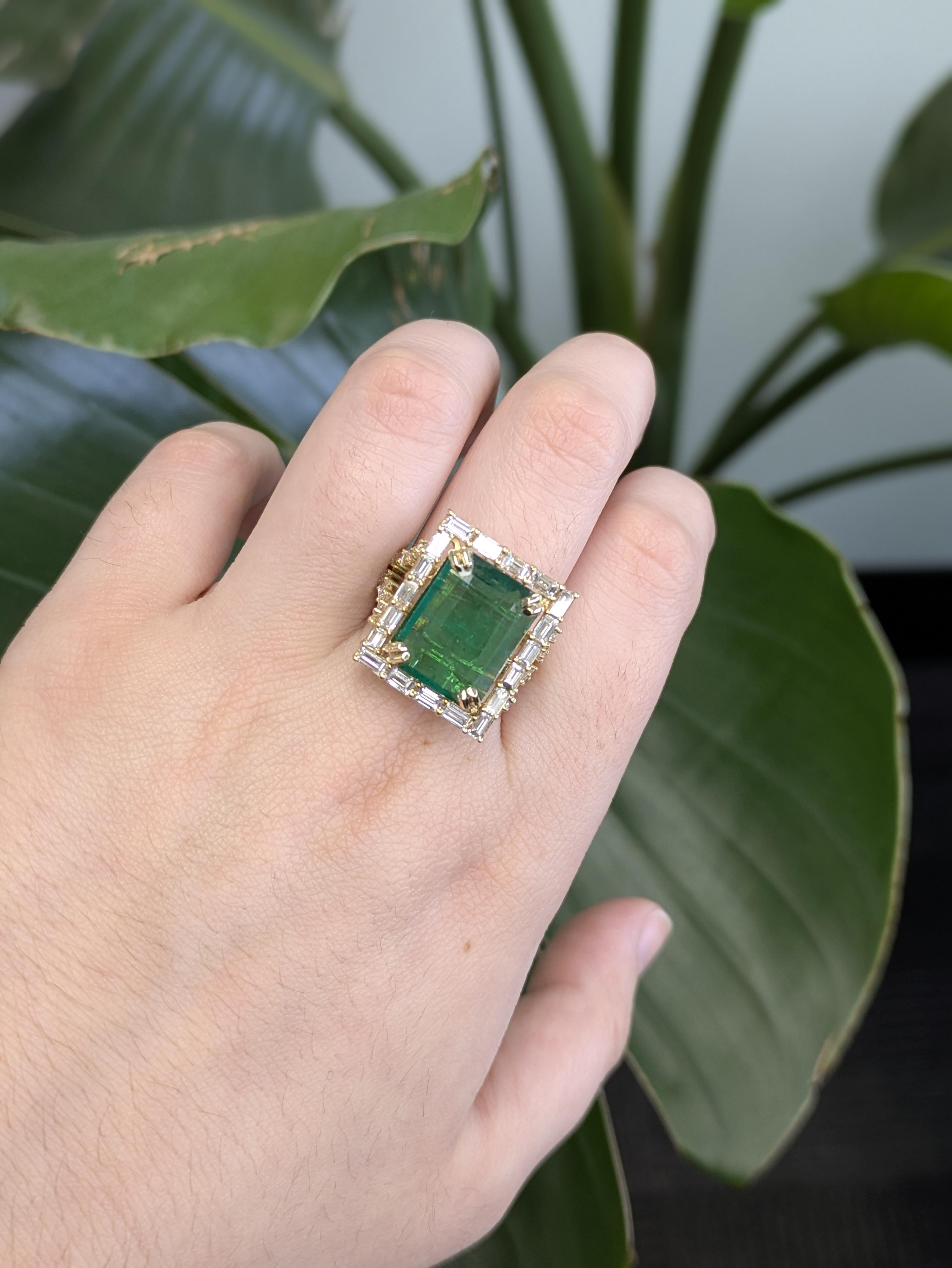 Dieser luxuriöse Ring enthält einen auffälligen sambischen Smaragd von 7,5 Karat im Smaragdschliff, der 14,5 x 12 mm misst. Der leuchtend grüne Mittelstein ist in 14-karätigem Gold (6,87 g) gefasst und wird von 36 schillernden Diamanten mit einem