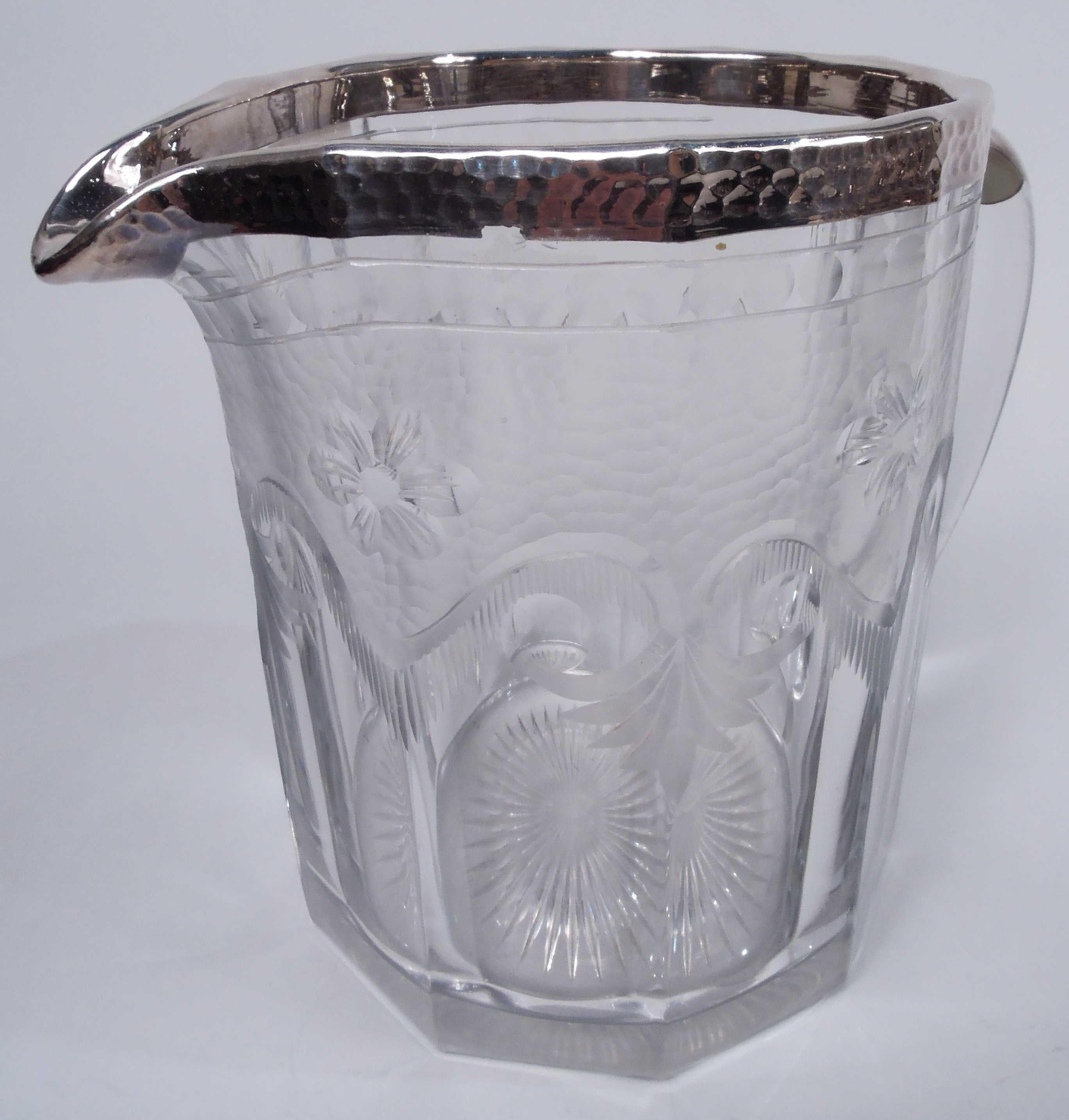 Edwardian Regency glass and silver water pitcher. Made by Heisey in Ohio, ca 1910. Faceted; top half has acid-etched beading, craquelure, and volute-scroll swags with pendant leaves. Mouth and u-spout have hand-hammered silver collar. C-scroll