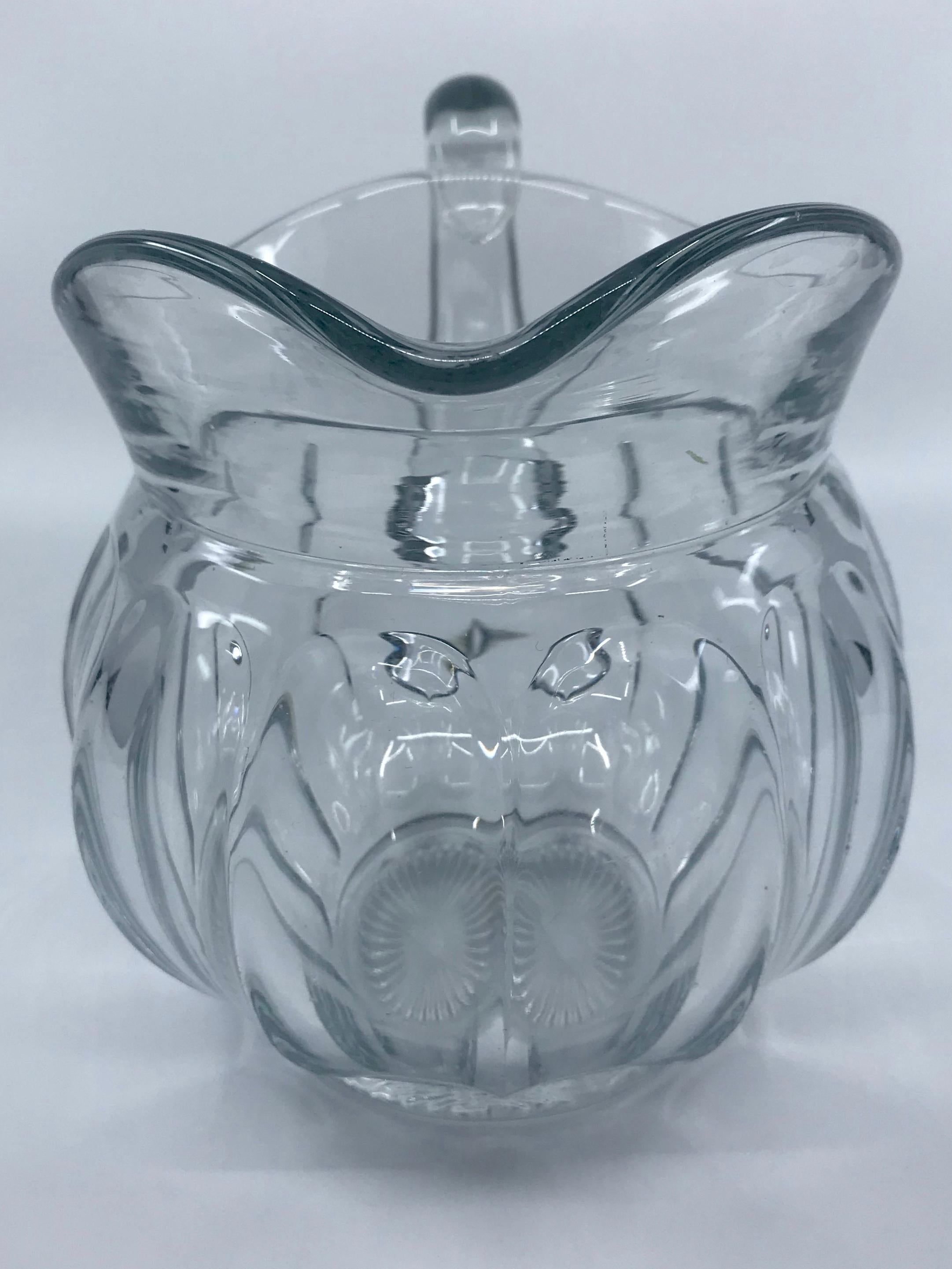 Paneled American glass pitcher. Vintage clear Heisey glass pitcher with bulbous paneled form and cut starburst to bottom with trademark for A.H. Heisey & Co  of H within the diamond mark. United States first half 20th century
Dimensions: 6.25