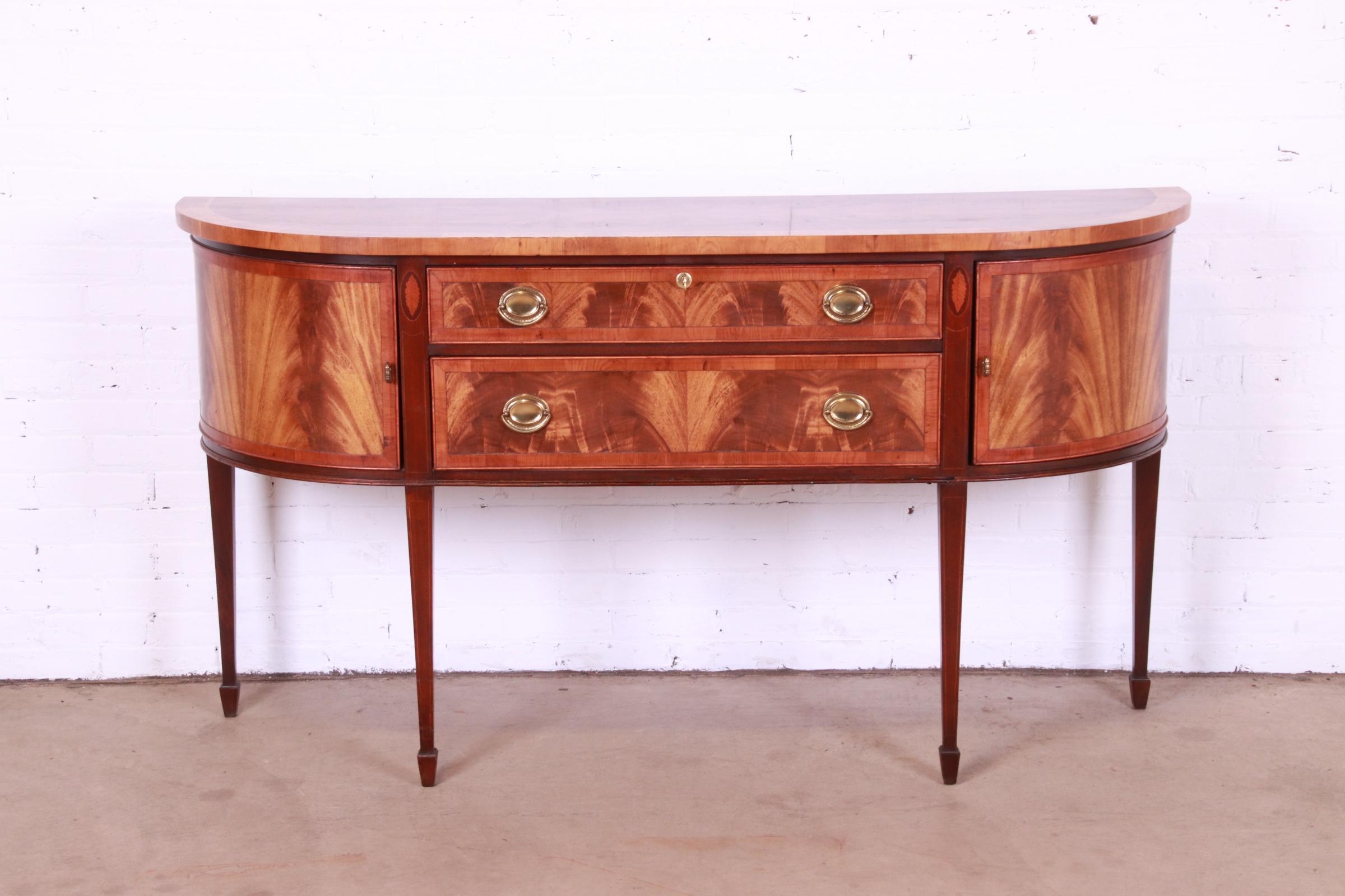 A beautiful Hepplewhite or Federal style demilune sideboard, buffet, or credenza.

By Hekman

USA, late 20th century

Gorgeous book-matched flame mahogany, with yew wood banding, satinwood inlay, and original brass hardware. Top drawer locks,