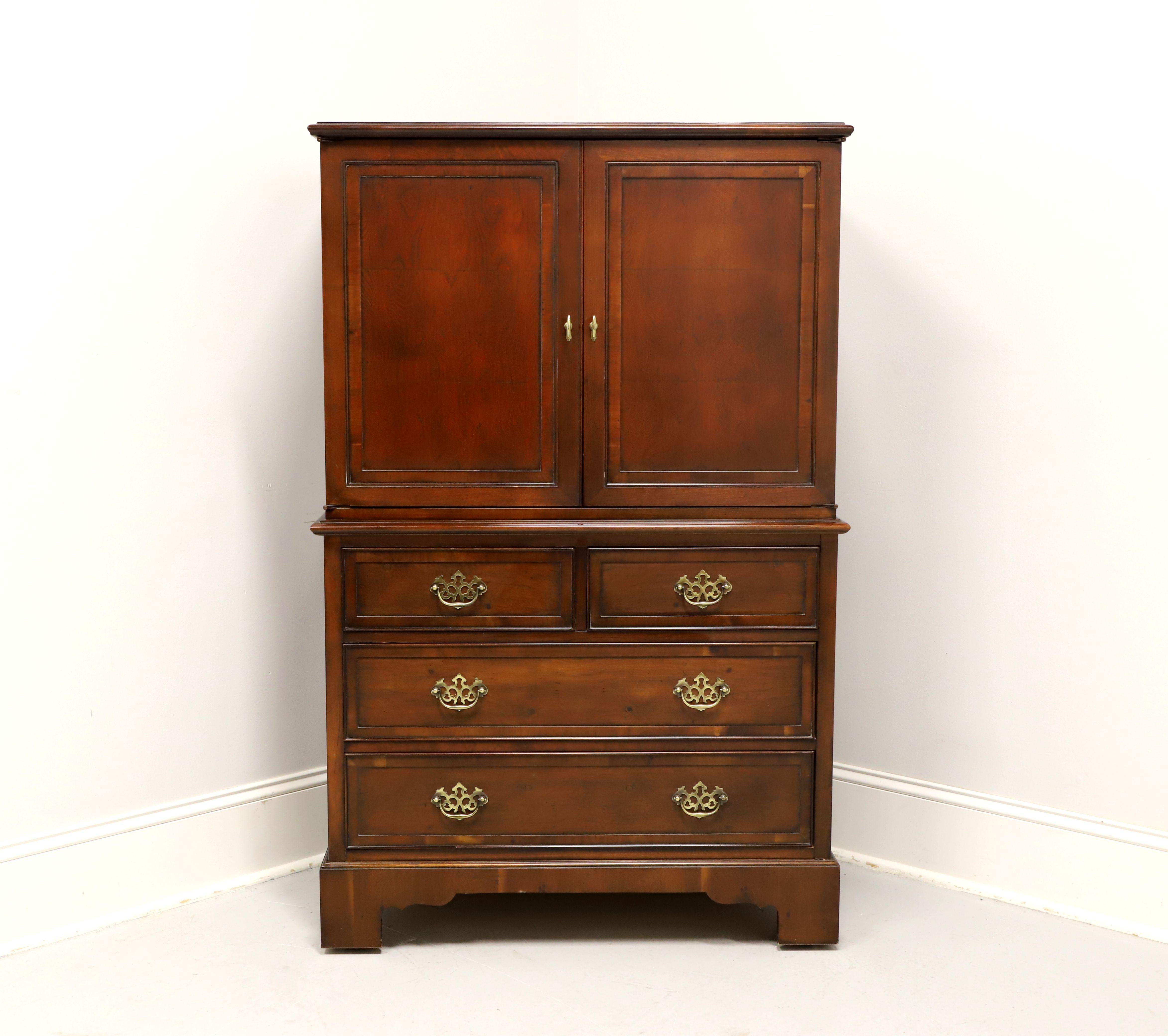 A Chippendale style entertainment cabinet chest by Hekman. Inlaid yew wood with brass hardware, ogee edge to top, ogee edge at middle to separate cabinet from chest, and bracket feet. Features upper cabinet with two fold back doors above two smaller
