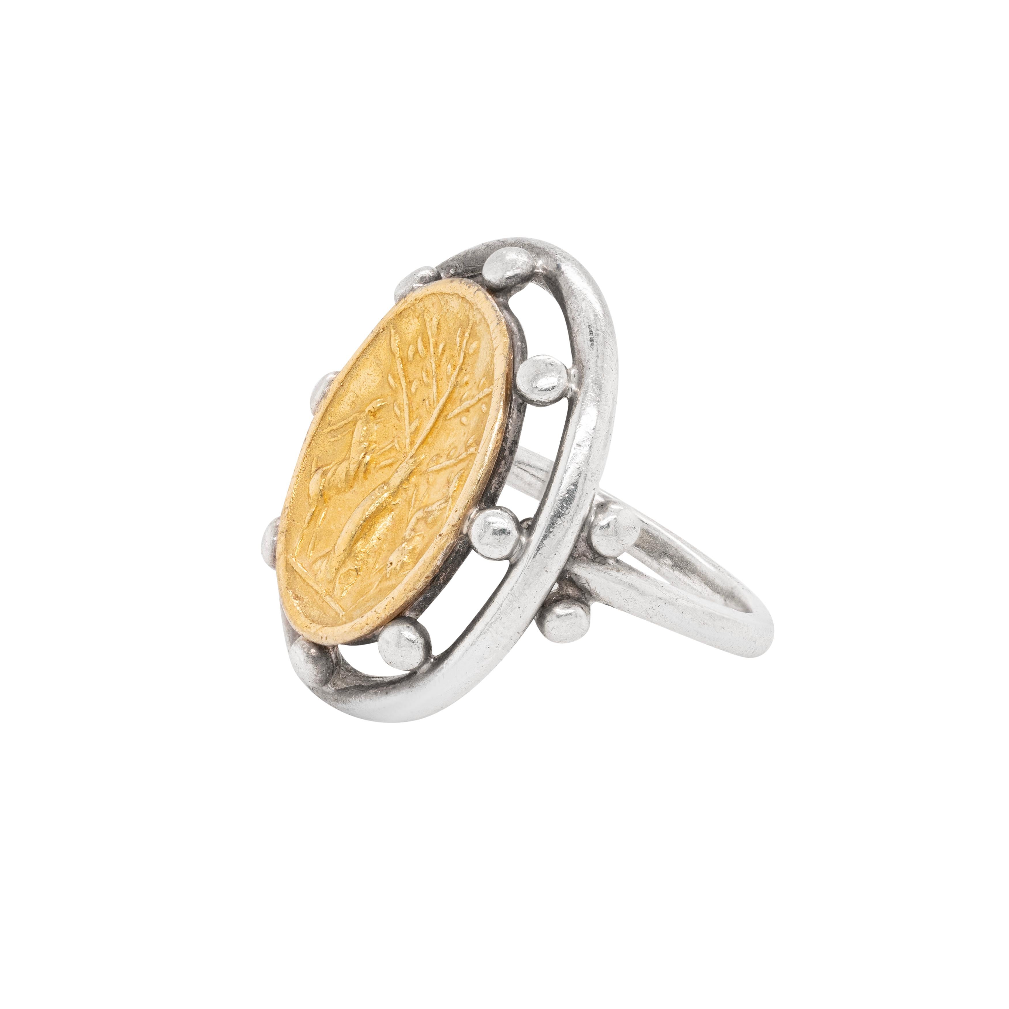 This gorgeous ring by famous designer Helen Woodhull showcases an open work design centred with a 22 carat yellow gold oval shaped intaglio depicting an antelope and tree scene. The centrepiece is beautifully connected to the sterling silver mount
