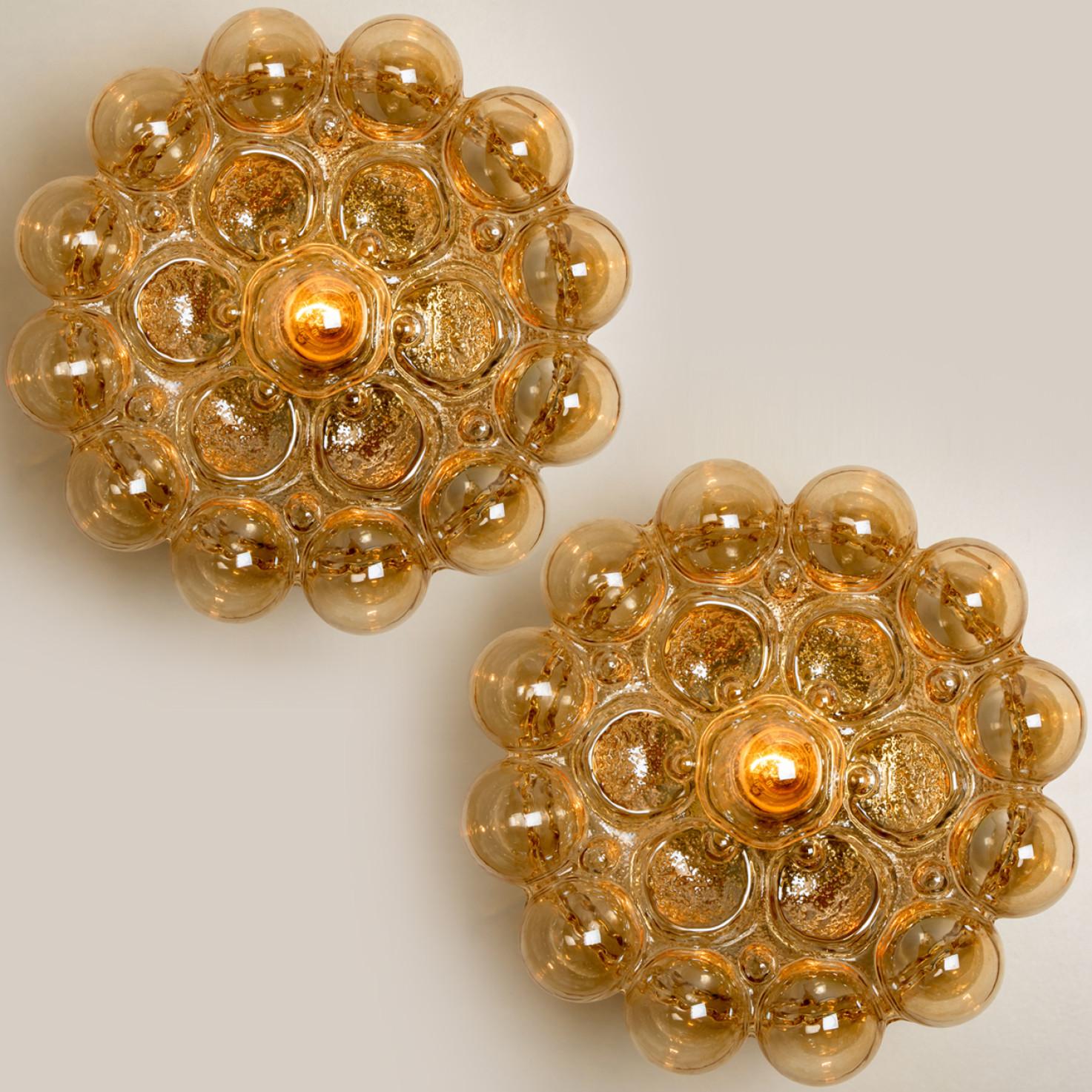 Beautiful high-end large bubble wall lights/ flush mounts by Helena Tynell for Glashütte Limburg, Germany, 1960s.
Made of glossy amber colored glass with a brass colored base. Illuminates beautifully.

The price is per piece. They will be sold