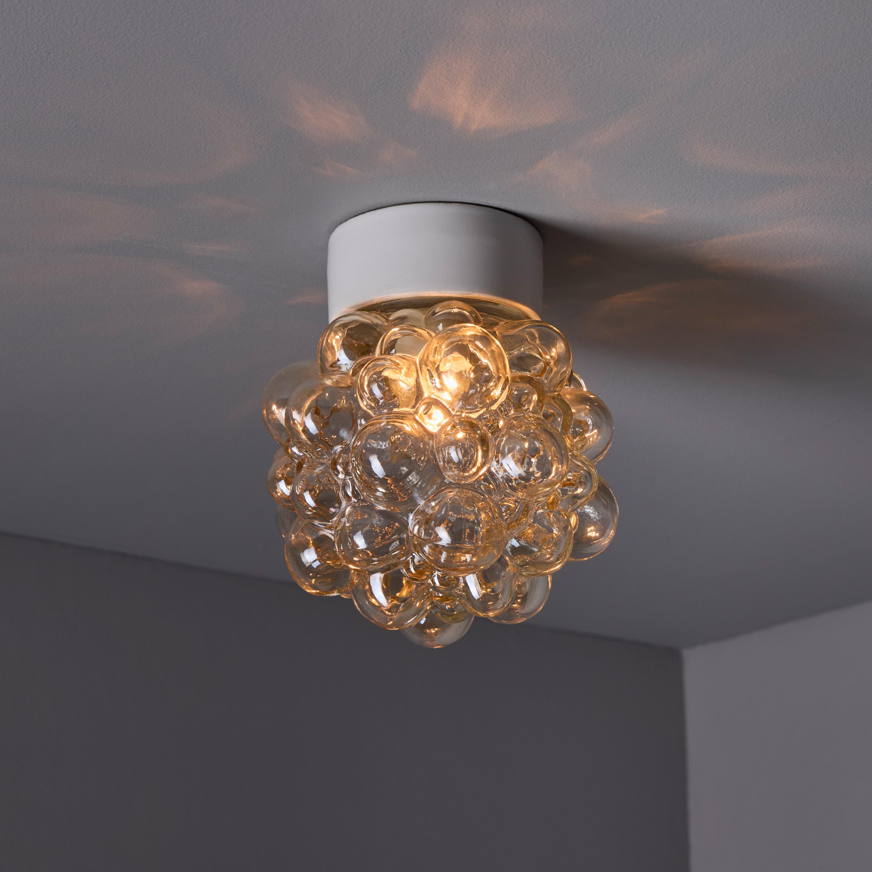 Helena Tynell Amber Bubble Glass Wall or Ceiling Lamp.

Executed in thick and heavy textured light amber bubble glass and white porcelain mount. Can be mounted on the ceiling or used as a wall lamp. Fabricated in Limburg, Germany circa 1960s.

A