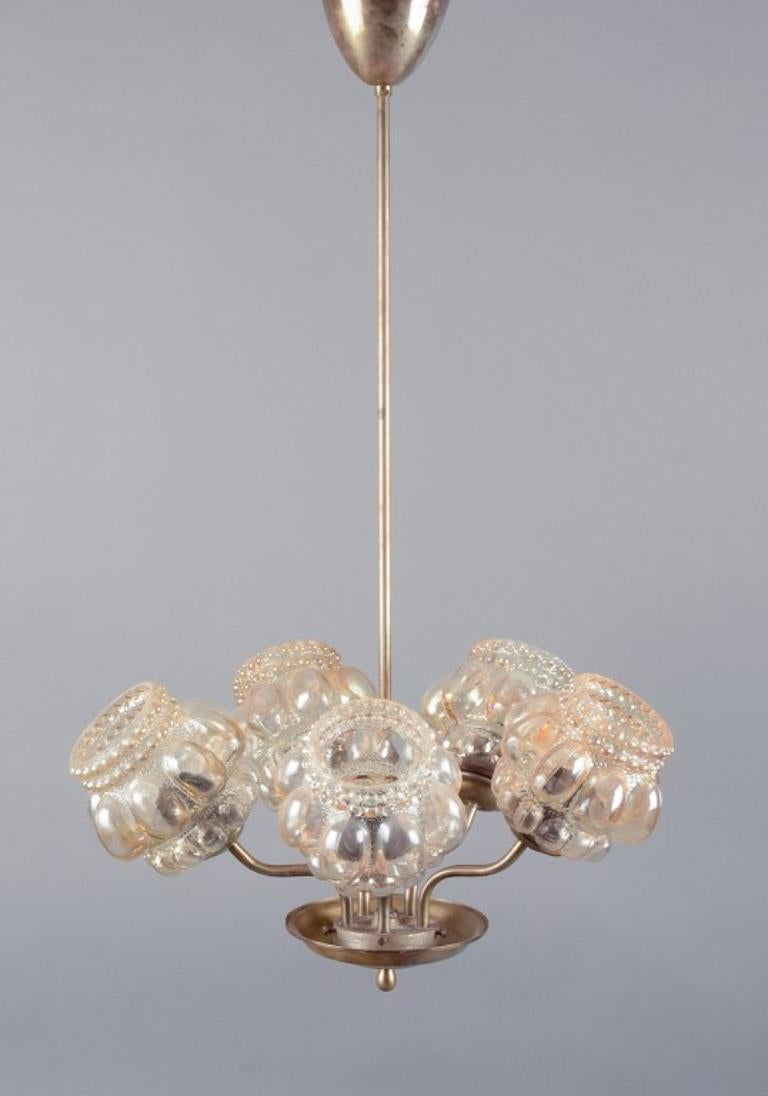 Helena Tynell (1918-2016), designer finlandese.
Lampada da soffitto a cinque bracci in ottone con paralumi in vetro color fumo.
1970s.
In perfette condizioni.
Dimensioni: H. H. 77,0 cm x L. 49,0 cm.

Helena Tynell era una rinomata artista finlandese