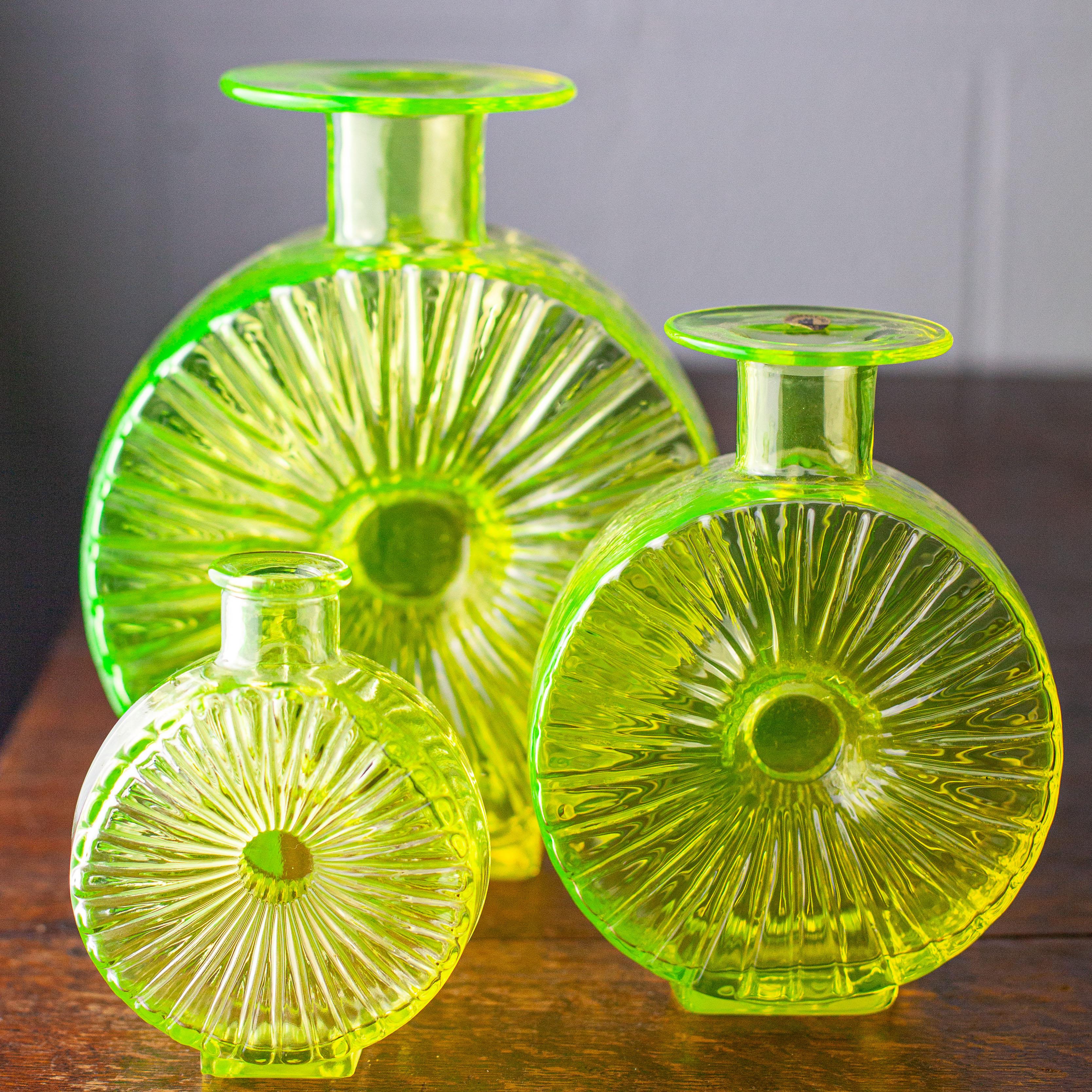A stunning collection of three Scandinavian uranium glass 'Aurinkopullo' (or Sun Bottle) decorative vases. Made by Riihimaki (also known as Riihimaen Lasi Oy) of Finland from 1964-1974 and designed by Helena Tynell in 1963. 

This is perhaps