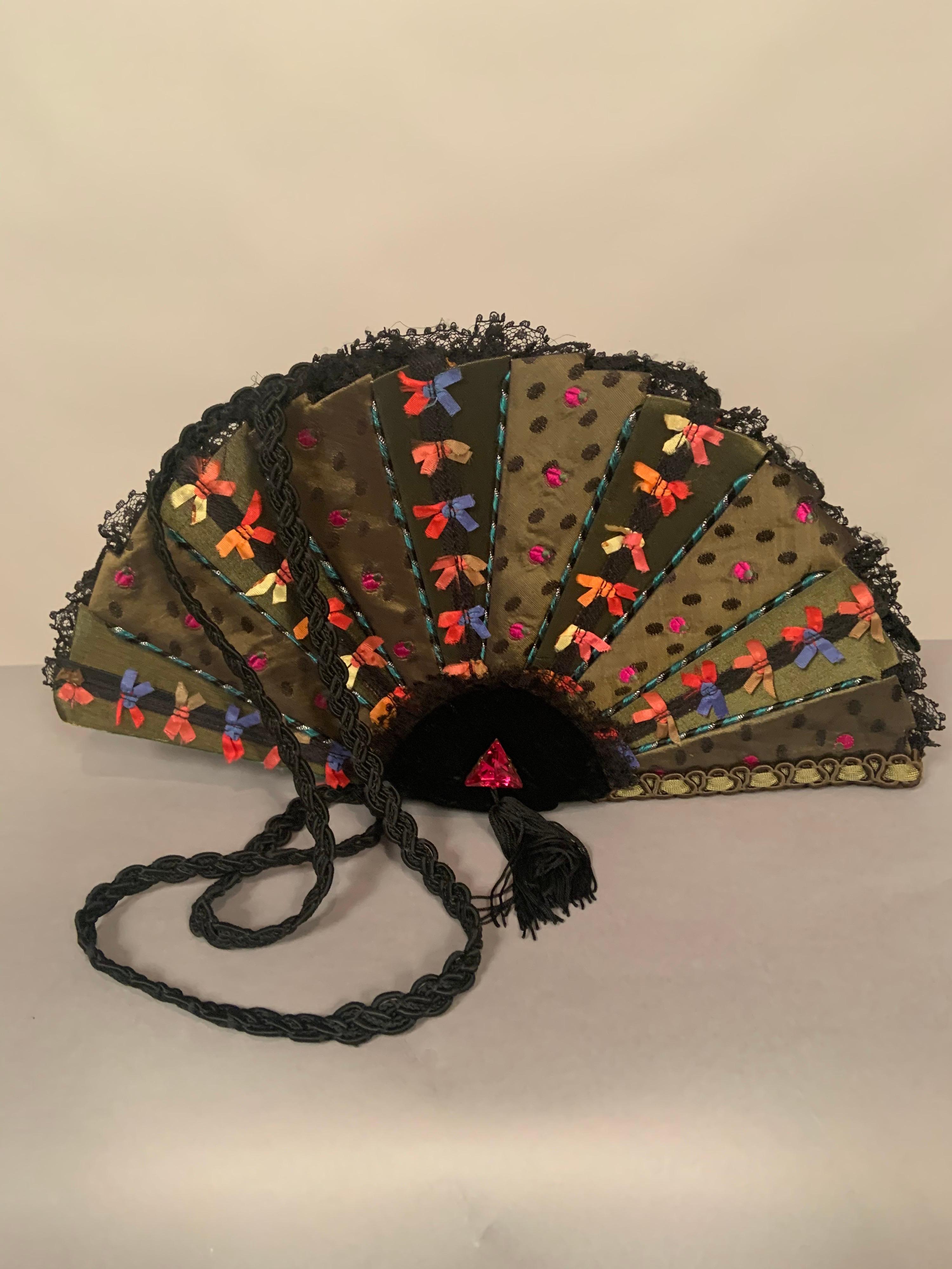 Helene Angeli, located in Nice, in the South of France, designs fanciful handbags in the shape of familiar objects. This bag representing a fan is covered with two different olive green silks, one solid fabric adorned with multi color bows, the