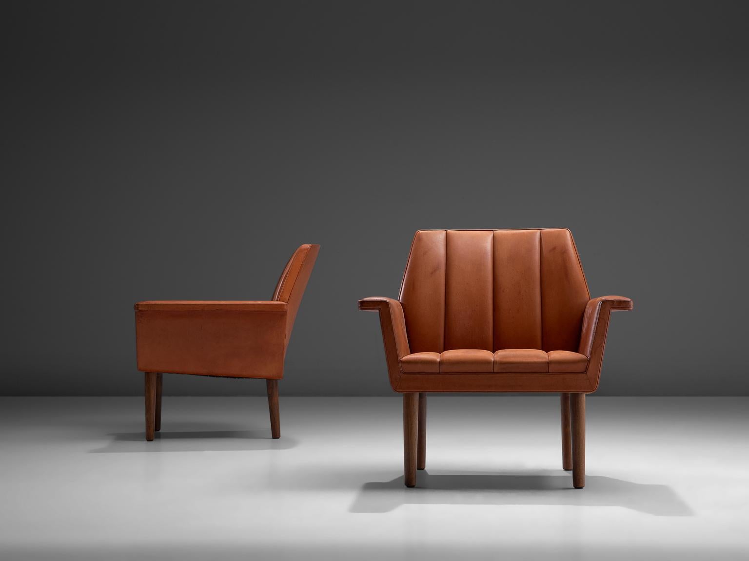 Set of two armchairs, in red leather and wood by Helge Vestergaard-Jensen for Peder Pedersen, Denmark, 1960. 

Pair of terracotta-red leather armchairs that stand high on their wooden legs, these chairs have a stately appearance. The seating is
