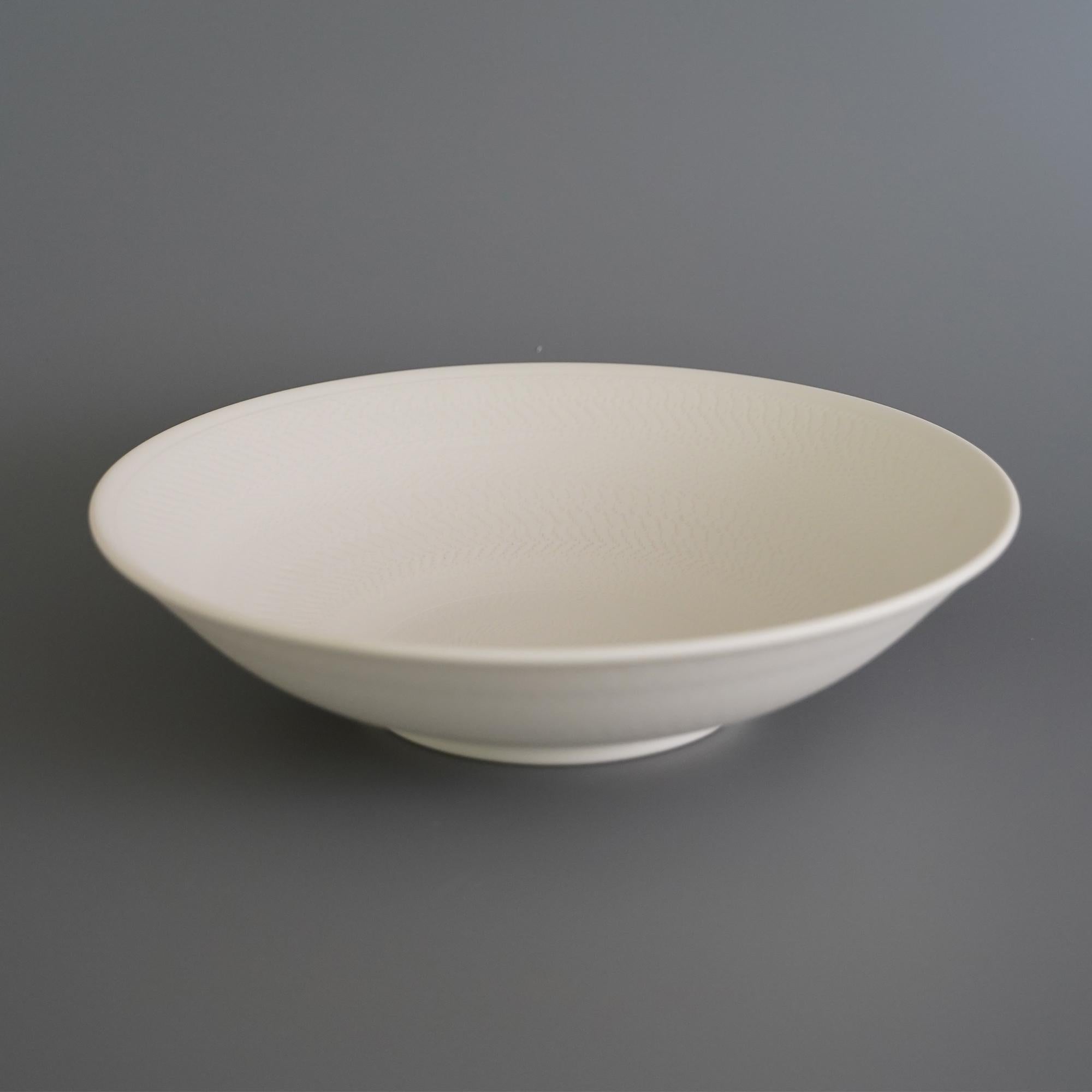 Helice fruit bowl by Studio Cúze.
Dimensions: W 27 x H 6.5 cm.
Materials: ceramic.

The Helice Fruit Bowl is an all-white bowl with a special quality and a unique handmade pattern. The bowl offers an even and precise shape, which is perfectly