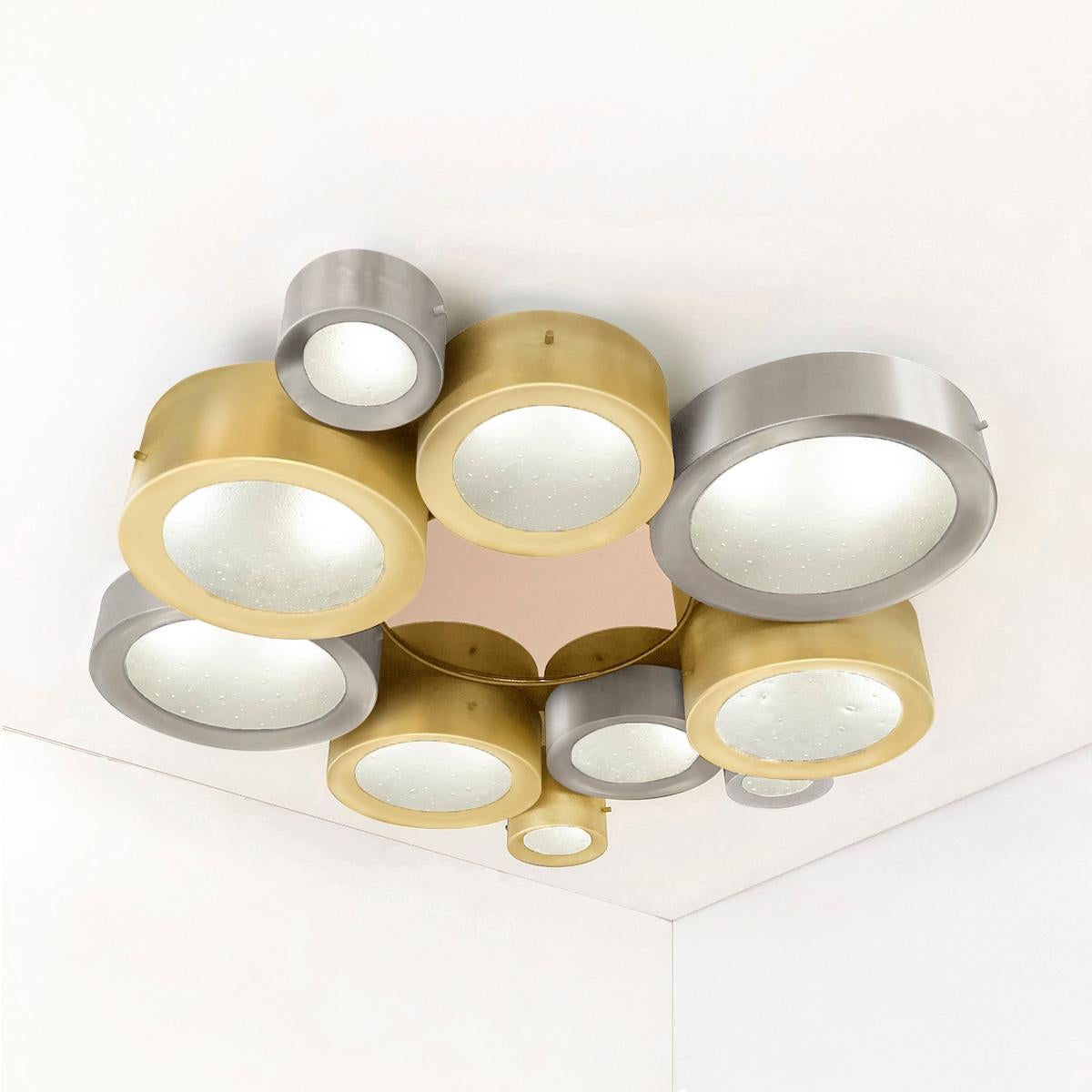 The Helios ceiling light features an imposing composition of illuminated Murano glass shades gravitating around a central tinted mirror. The first images show the fixture in satin brass and satin nickel with a rose center mirror-subsequent pictures