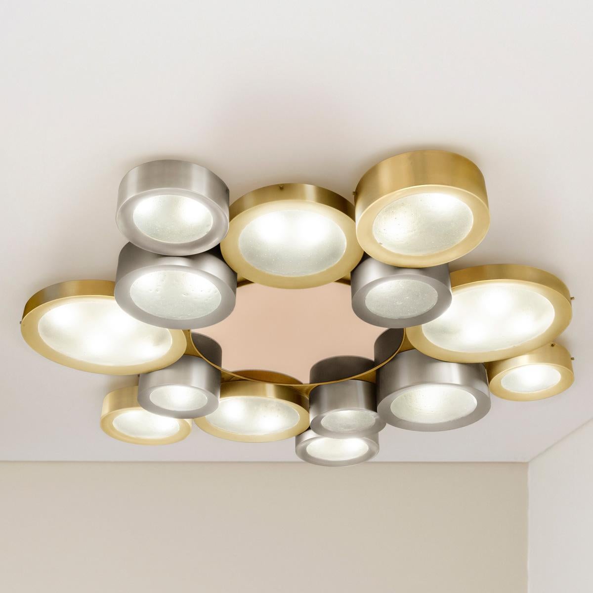 The Helios ceiling light features an imposing composition of illuminated Murano glass shades gravitating around a central tinted mirror. The first images show the fixture in a satin brass and satin nickel finish with a rose center mirror-subsequent