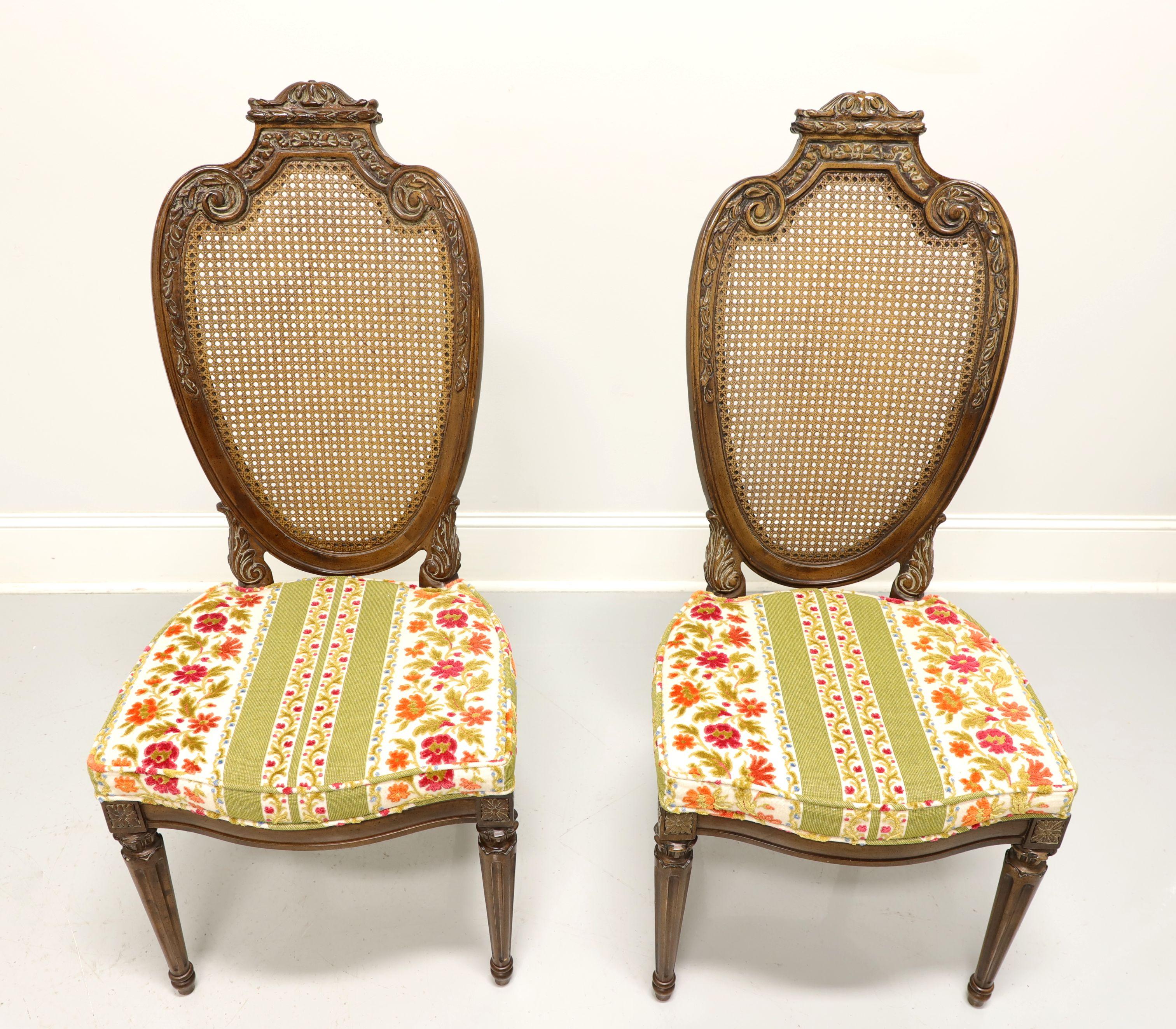 A pair of French Provincial Louis XVI style dining side chairs by Hellam. Walnut, slightly distressed, with caned decoratively carved oval shield like backs, floral brocade fabric upholstered seats, carved apron, turned and fluted front legs. Made
