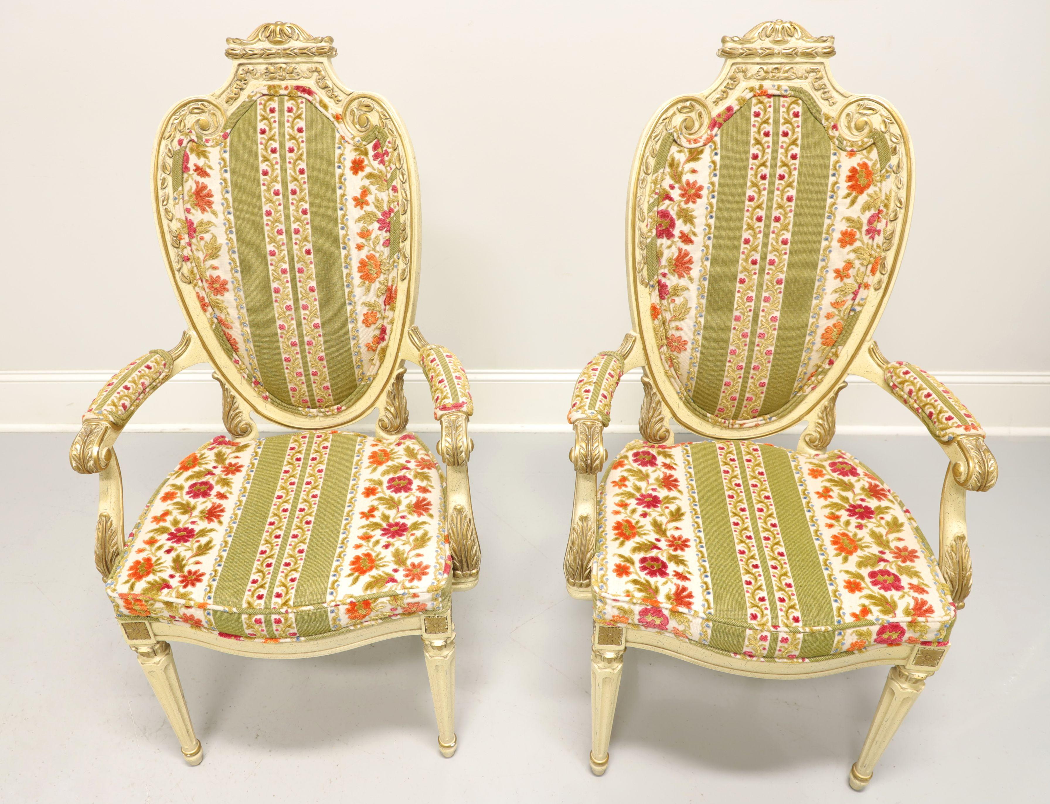 A pair of French Provincial Louis XVI style dining armchairs by Hellam. Walnut, slightly distressed, painted an antique white with gold accents, caned decoratively carved oval shield like backs, floral brocade fabric upholstered scroll arms & seats,