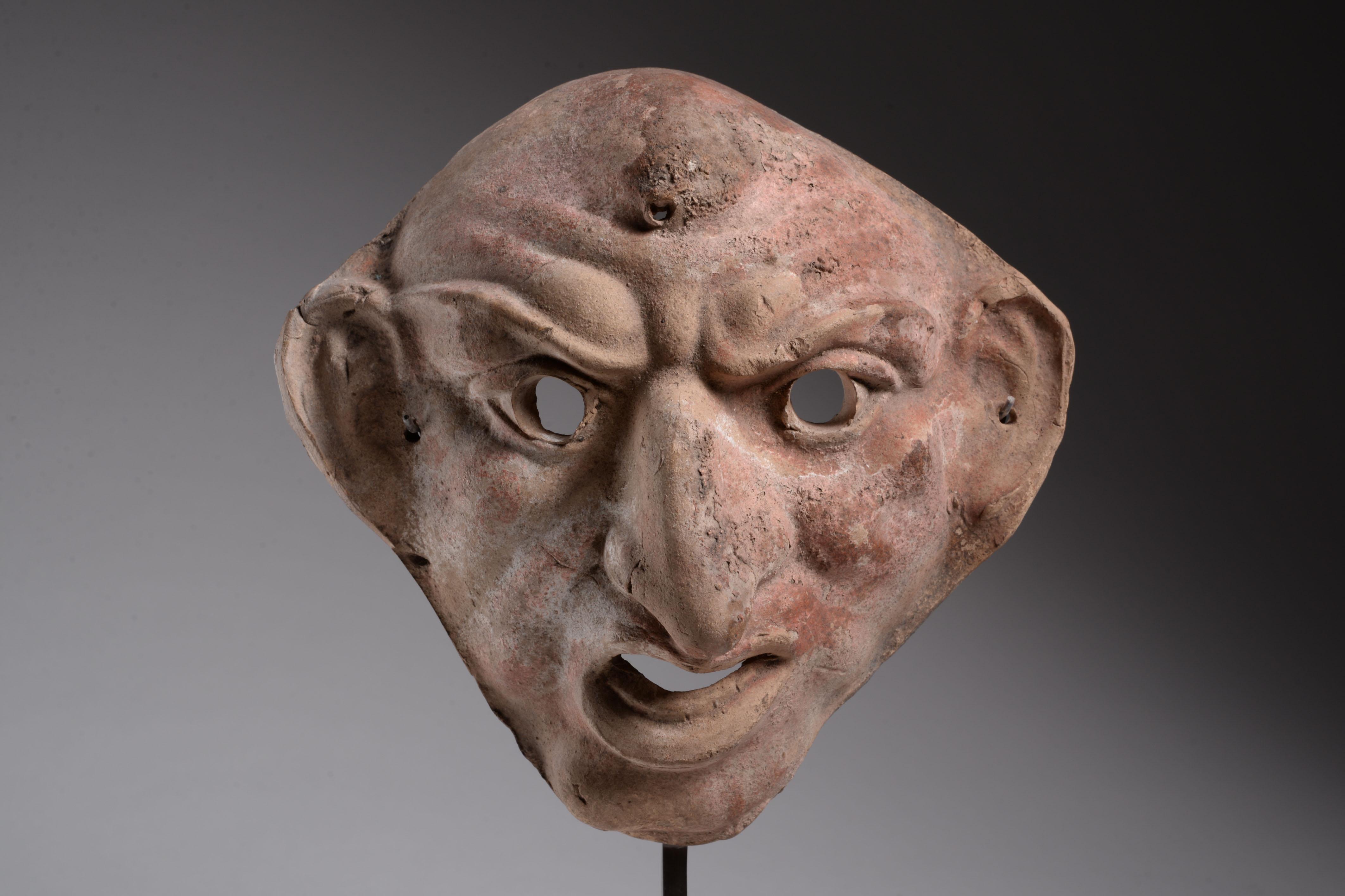 Grotesque theatrical mask of Maccus
Late Hellenistic or Early Imperial period, circa 1st century B.C. – 1st century A.D., likely from Southern Italy.
Terracotta with remains of pink and white pigment
Measure: Height: 20 cm. 
With old label