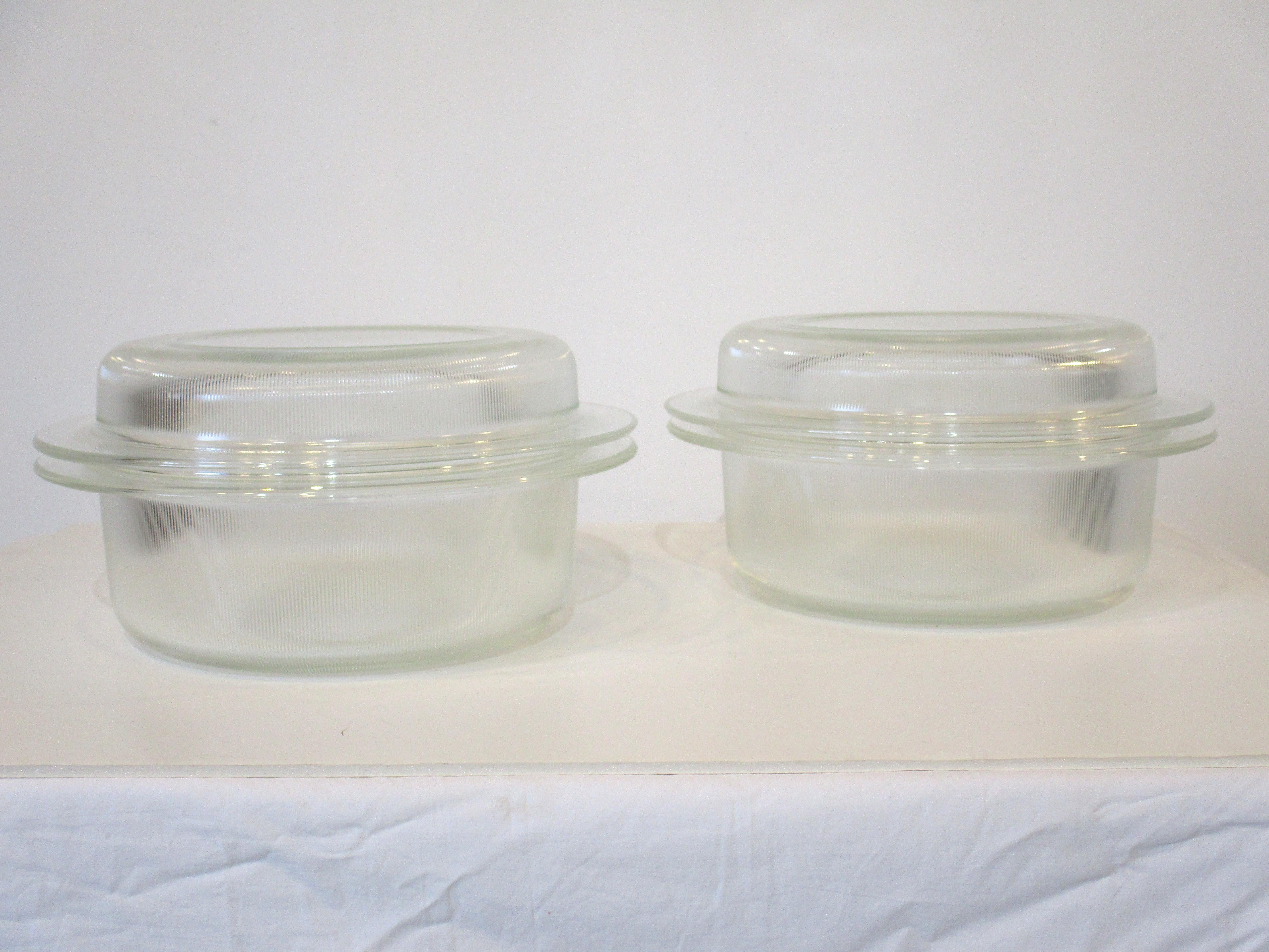 A set of two glass Heller bakeware pieces with lids designed by L & M Vignelli that can be used in the oven, microwave or as severing pieces. The lids can be used as pie pans so the four pieces are very versatile they hold 3 quarts and are the