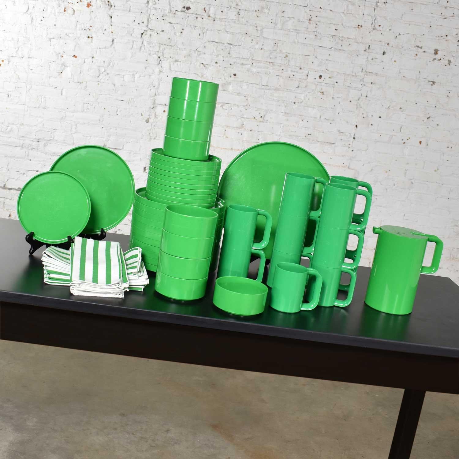 Large beautiful 58-piece set of Melamine dinnerware designed by Massimo and Lella Vignelli for Heller in Kelly green. Plus, matching green and white striped Marimekko by Fallani and Cohn napkins. This set includes 12 dinner plates, 11 salad plates,