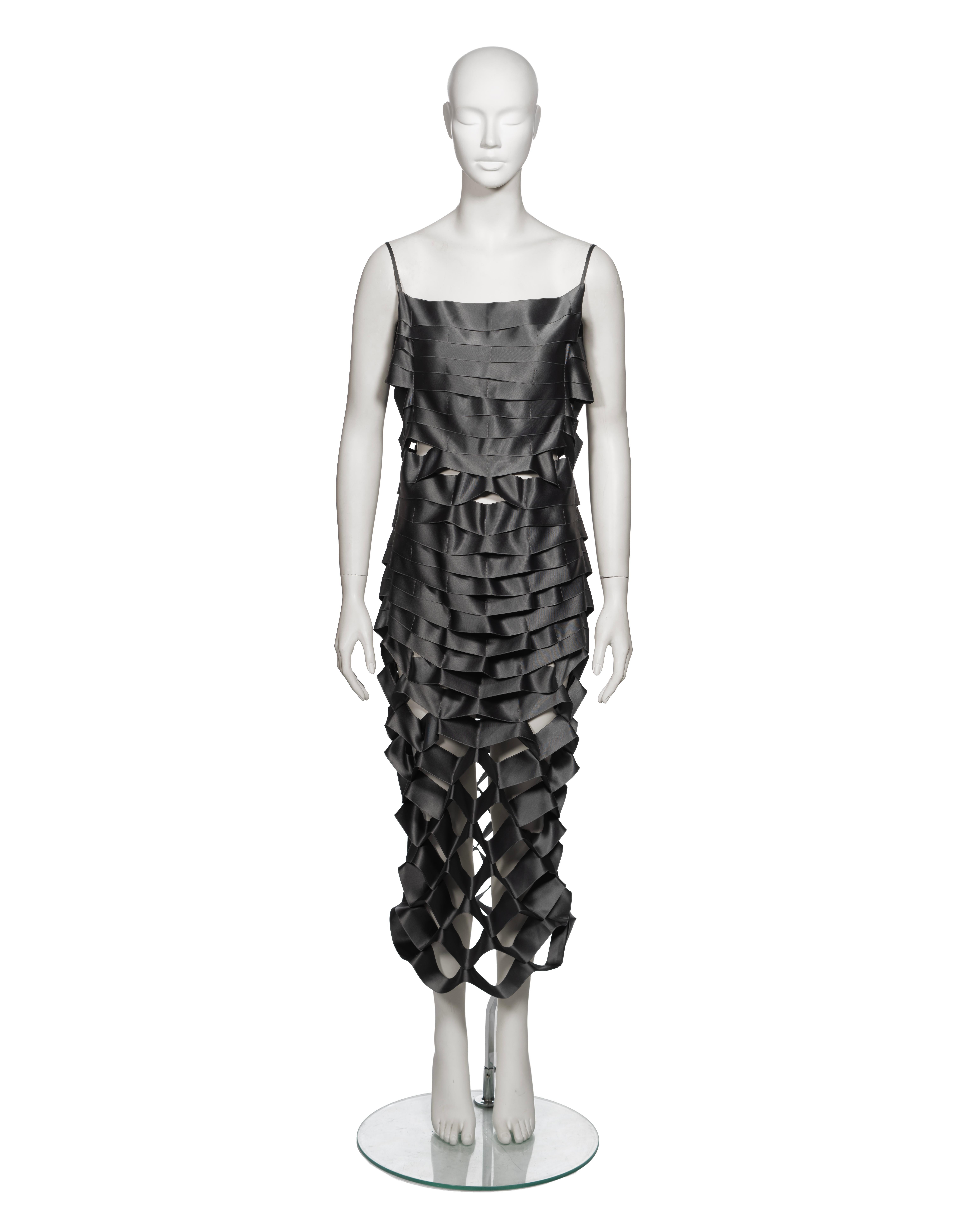 ▪ Archival Helmut Lang 'Ribbon' Dress
▪ Creative Director: Helmut Lang
▪ Spring-Summer 1998
▪ Sold by One of a Kind Archive
▪ Museum Grade
▪ Entire construction crafted from gunmetal satin ribbon bands
▪ Ribbons intricately layered, gradually