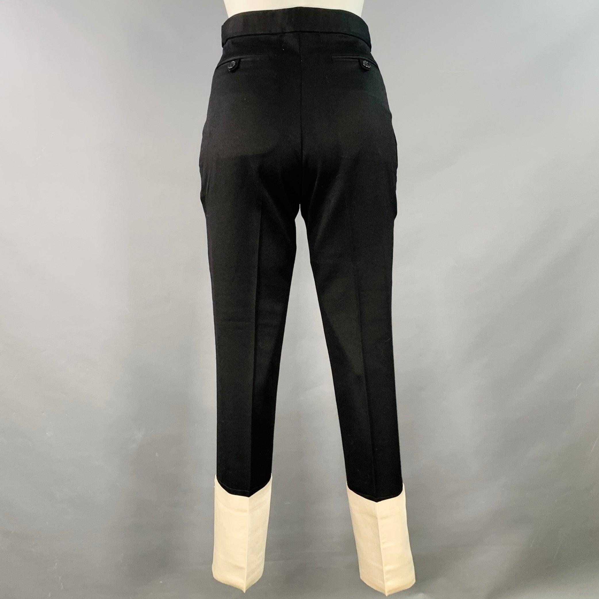Pantalon habillé HELMUT LANG
en tissu noir (au toucher laine) avec poignets en satin blanc contrastant, pattes latérales et fermeture à glissière.Bon état d'occasion. Marques modérées sur les poignets, en l'état. Toutes les étiquettes sauf celles de