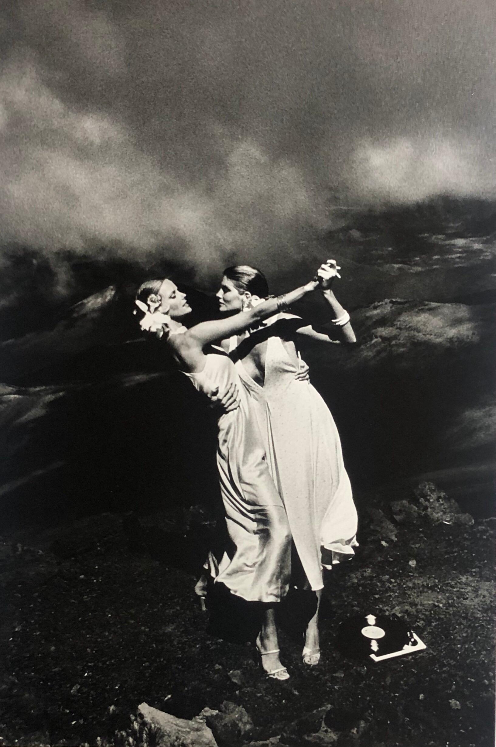 In "Rene Russo und Cheryl Tiegs, Hawaii, 1974" hält Helmut Newton die beiden berühmten Model-Schauspielerinnen bei einem Fotoshooting am berühmten Halealakal-Krater auf Hawaii fest, wo sie neben einem Plattenspieler auf dem Vulkan tanzen.   Das Bild