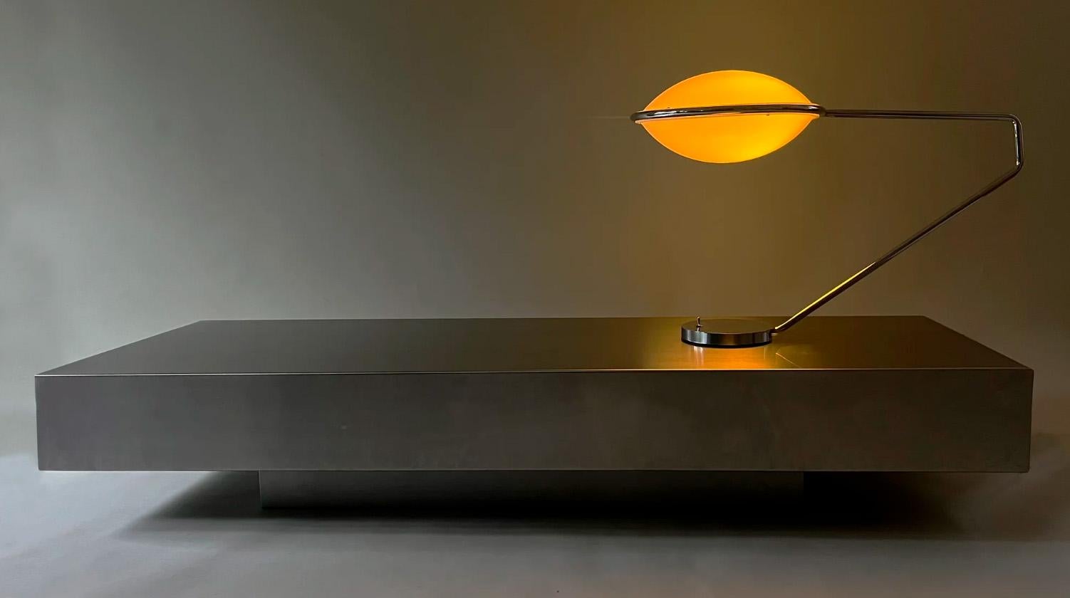 Desk lamp that projects a precise and restrained amber light.
With a circular chrome base and a slender arm that supports the thermoformed acrylic shades, Helo creates a warm atmosphere on a minimal scale.
A functional piece with a retro-futuristic