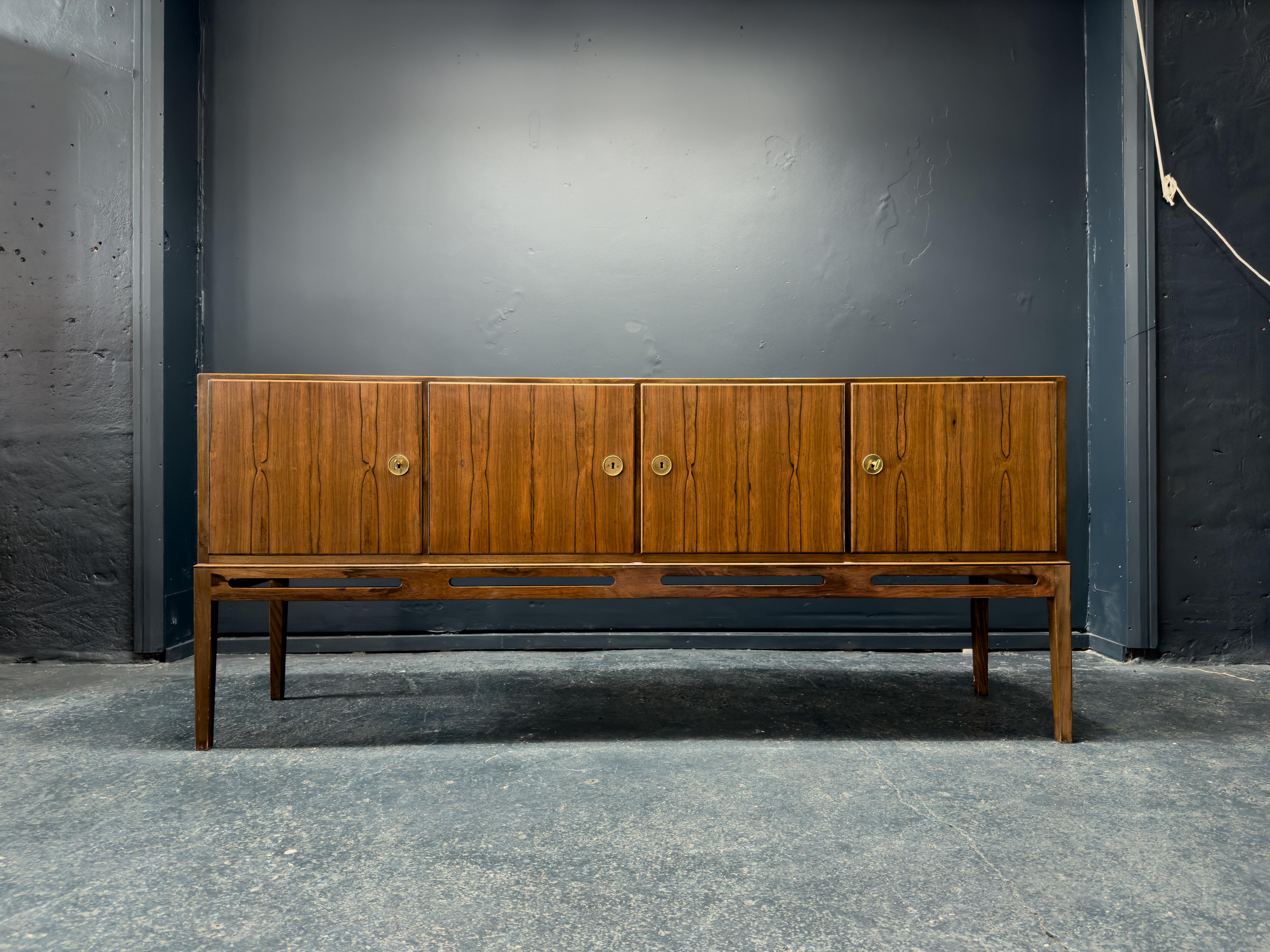 Produced by Heltborg Mobler in Denmark 1960s this wonderful hardwood sideboard boasts an incredible grain and excellent size.

With four compartments housing shelving, this piece provides ample storage and versatile use. The brass hardware and