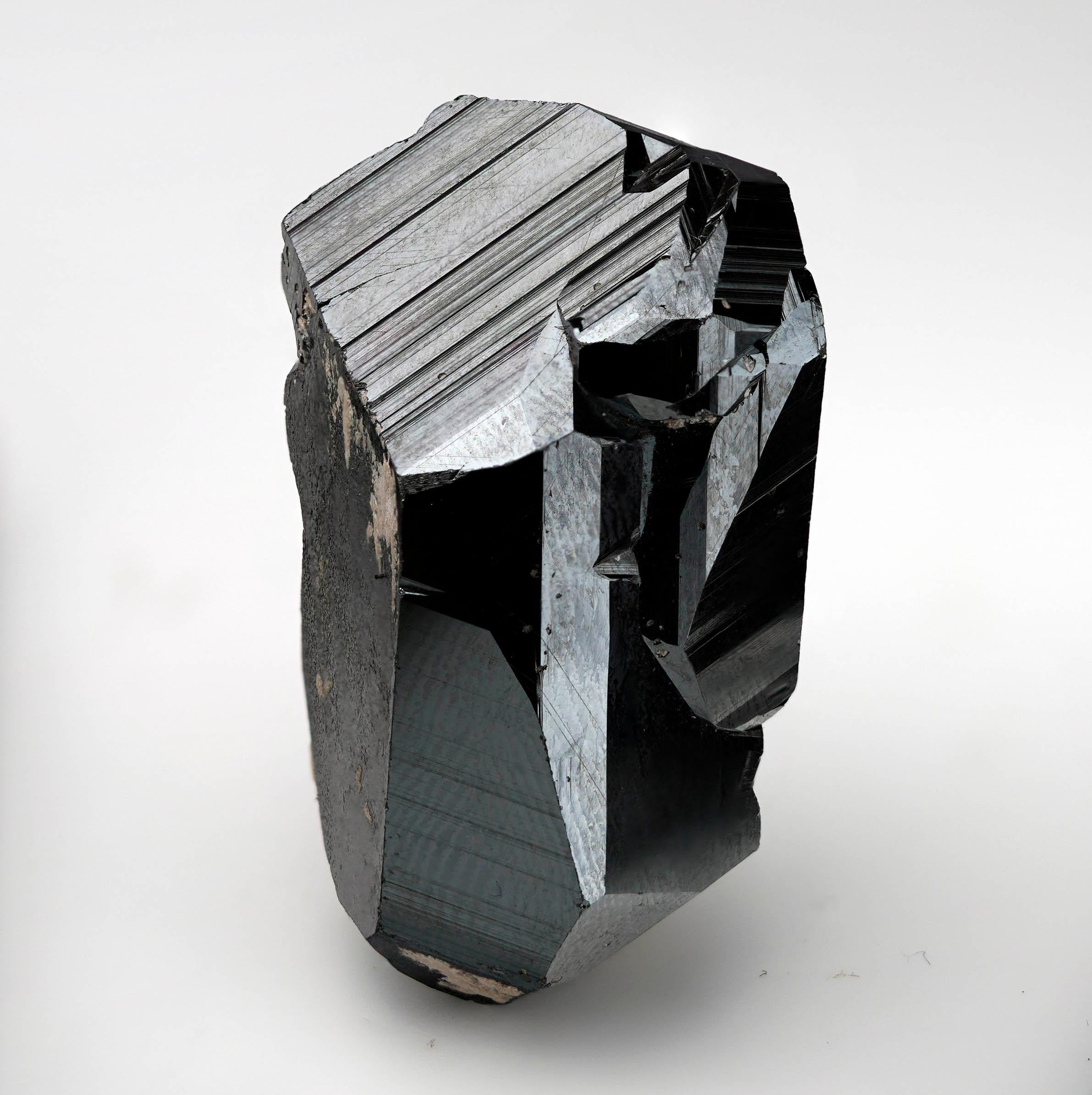 Questo straordinario cristallo singolo di ematite di grandi dimensioni, proveniente dalla rinomata miniera di Wessels nel Capo Settentrionale, in Sudafrica, presenta facce ben definite e una lucentezza metallica brillantemente riflettente per un