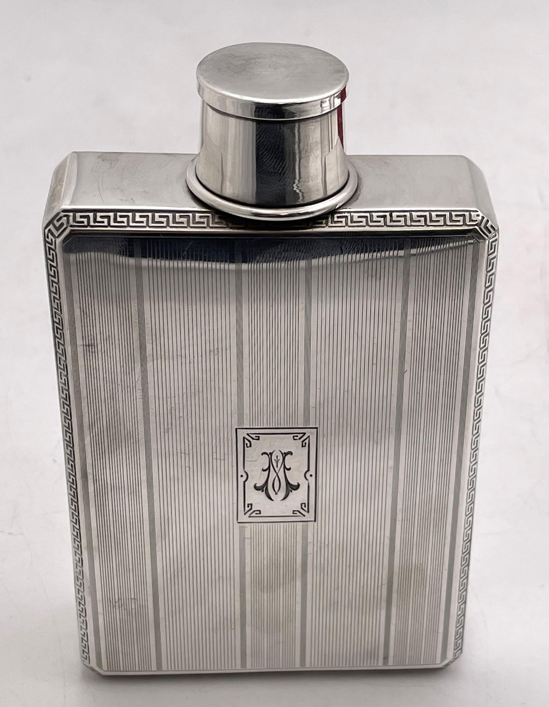 George Henckel & Co. sterling silver flask from the early 20th century, with an integrated collapsible shot glass whose maximum height is 1 3/4''. The flask measures 5'' by 3'' by 1 1/8'', can contain 2 pints, weighs 5.3 troy ounces, and bears