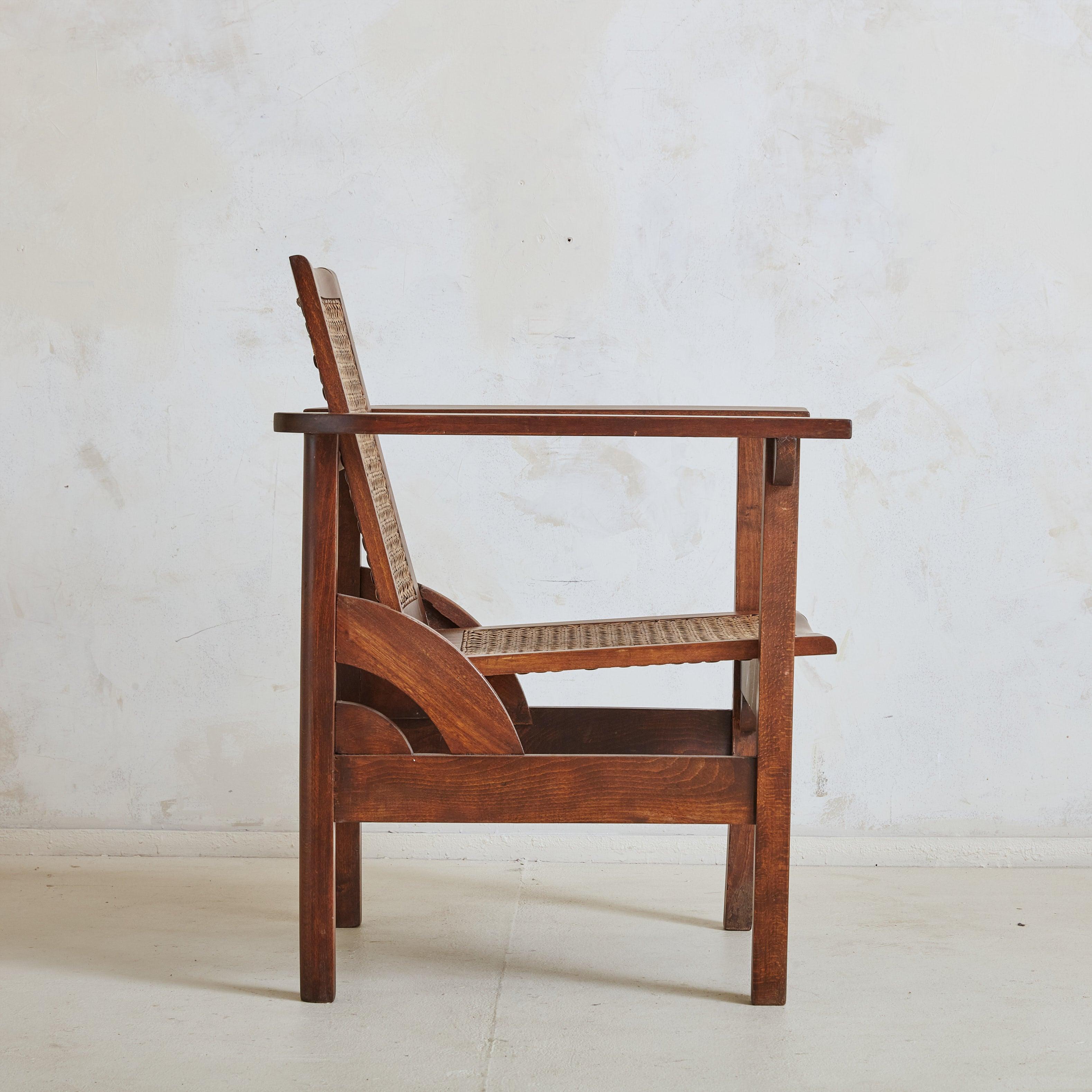A French 'Hendaye' armchair designed by Pierre Dariel in the 1930s. The chair's solid walnut frame is beautifully complemented by intricate cane weaving along the seat and backrest. The design features a unique folding backrest, allowing for three