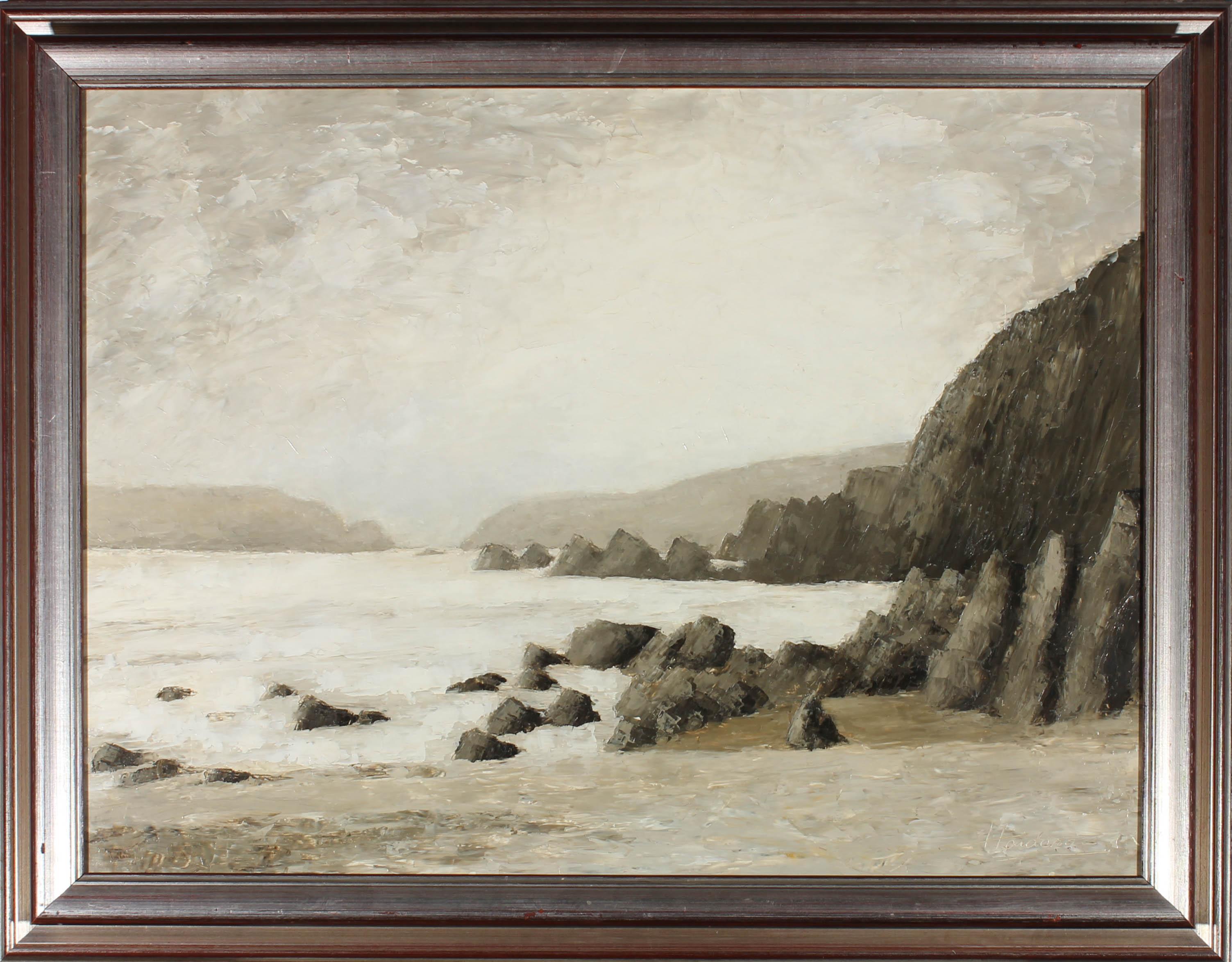 An atmospheric, moody coastal landscape showing monochrome cliffs with jagged rocks on the shore and small white waves rolling among them. The artist has signed to the lower right corner and the painting has been presented in a 20th Century silvered