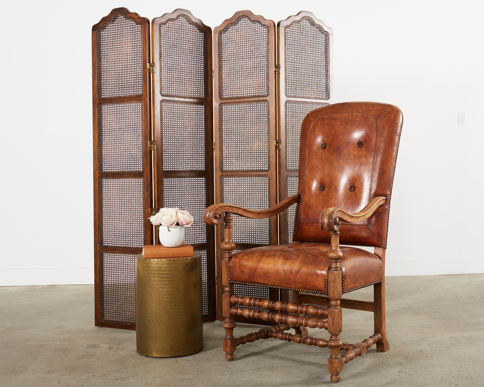 Grand hardwood and leather library armchair designed by Hendrix Allardyce in the Italian Baroque taste. The monumental chair features a hand-carved hardwood frame with large molded arms that gracefully curve and end with scrolled hands. The generous