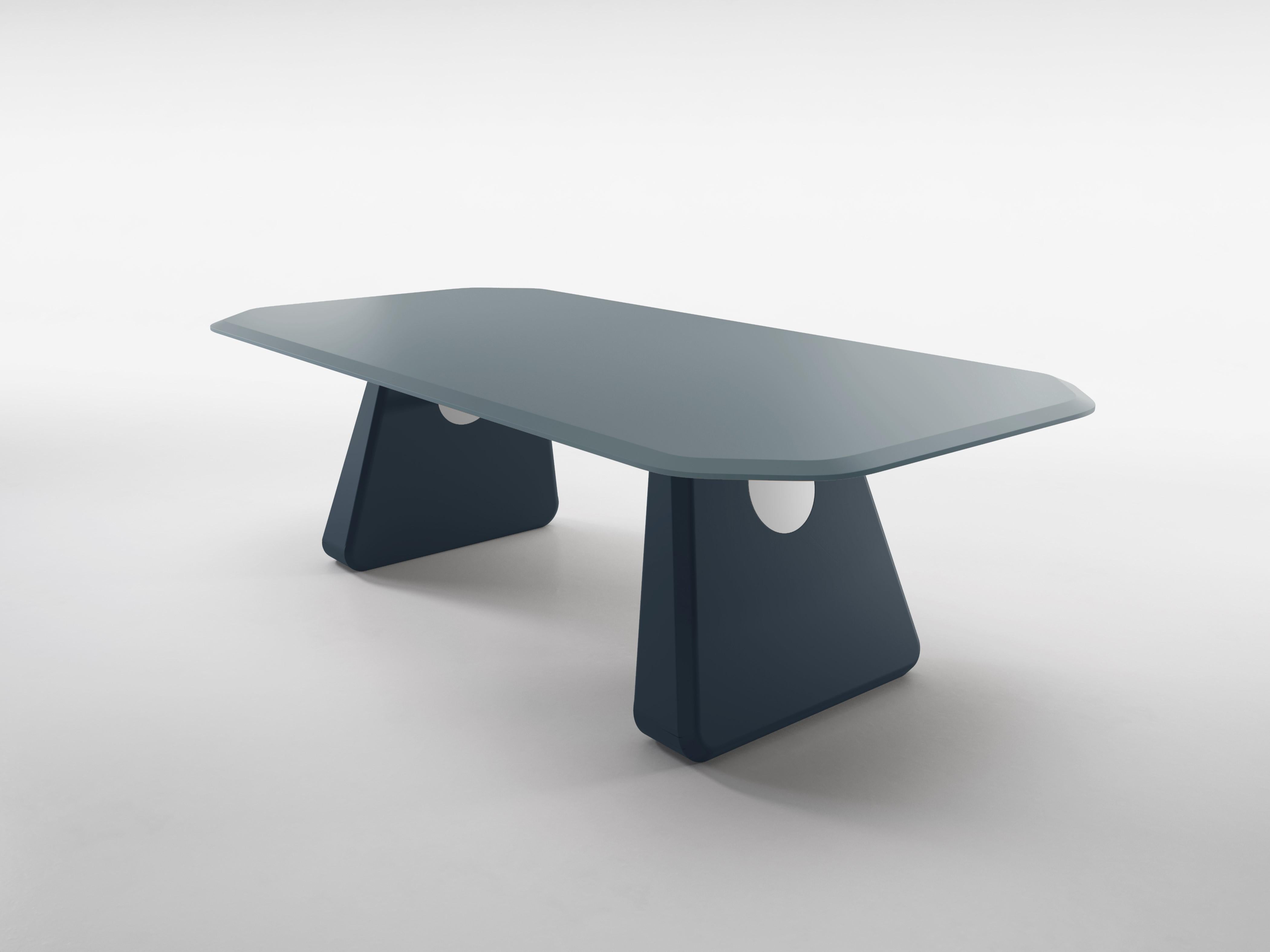 The Henge table features a lacquered top, supported by two large stone-like plinths. A beautifully detailed bar spans the distance between them and holds the two together. Henge takes its name from a famous rock formation in England but is heavily
