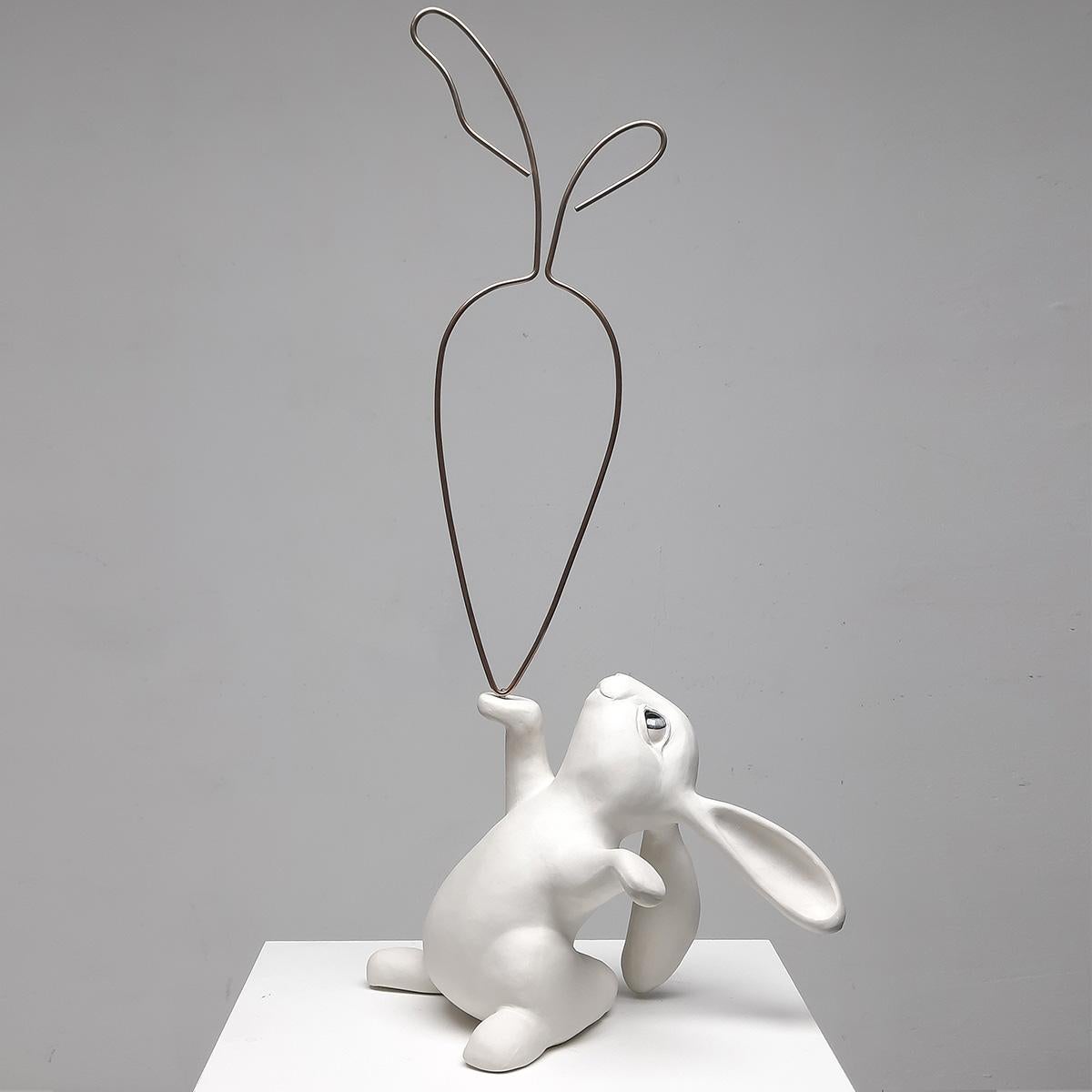 "24 Carrot Gold (White)" by Henk Jan Sanderman is a captivating ceramic tabletop sculpture that radiates elegance and charm. This original artwork features a beautifully crafted bunny rabbit, painted in pristine white, delicately holding a bronze