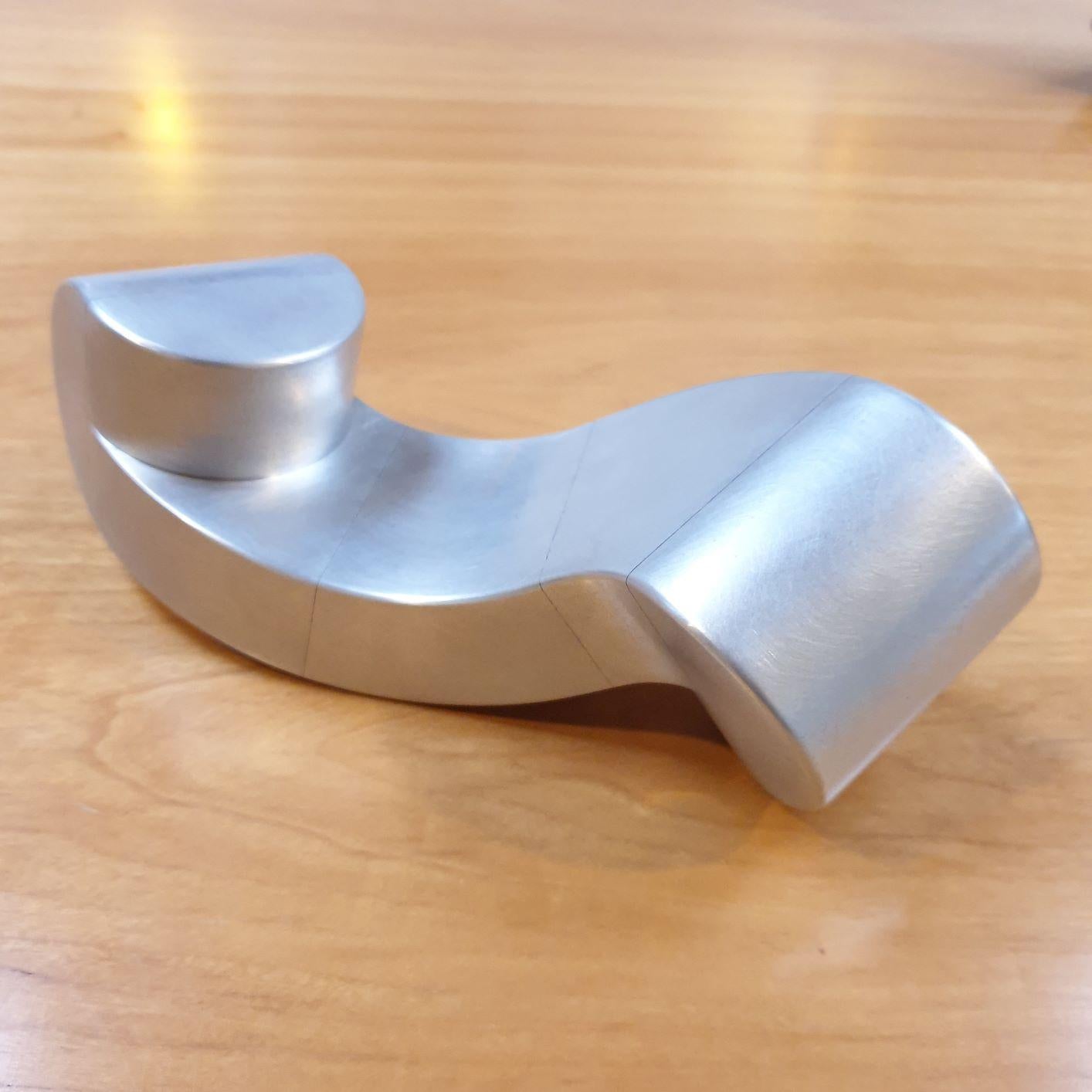 Banco (obra nº HVP01145) es una escultura geométrica abstracta moderna contemporánea de aluminio, de pequeño tamaño, del aclamado constructivista holandés Henk van Putten, nacido en Holanda, pero que durante muchos años vivió y trabajó en Auroville