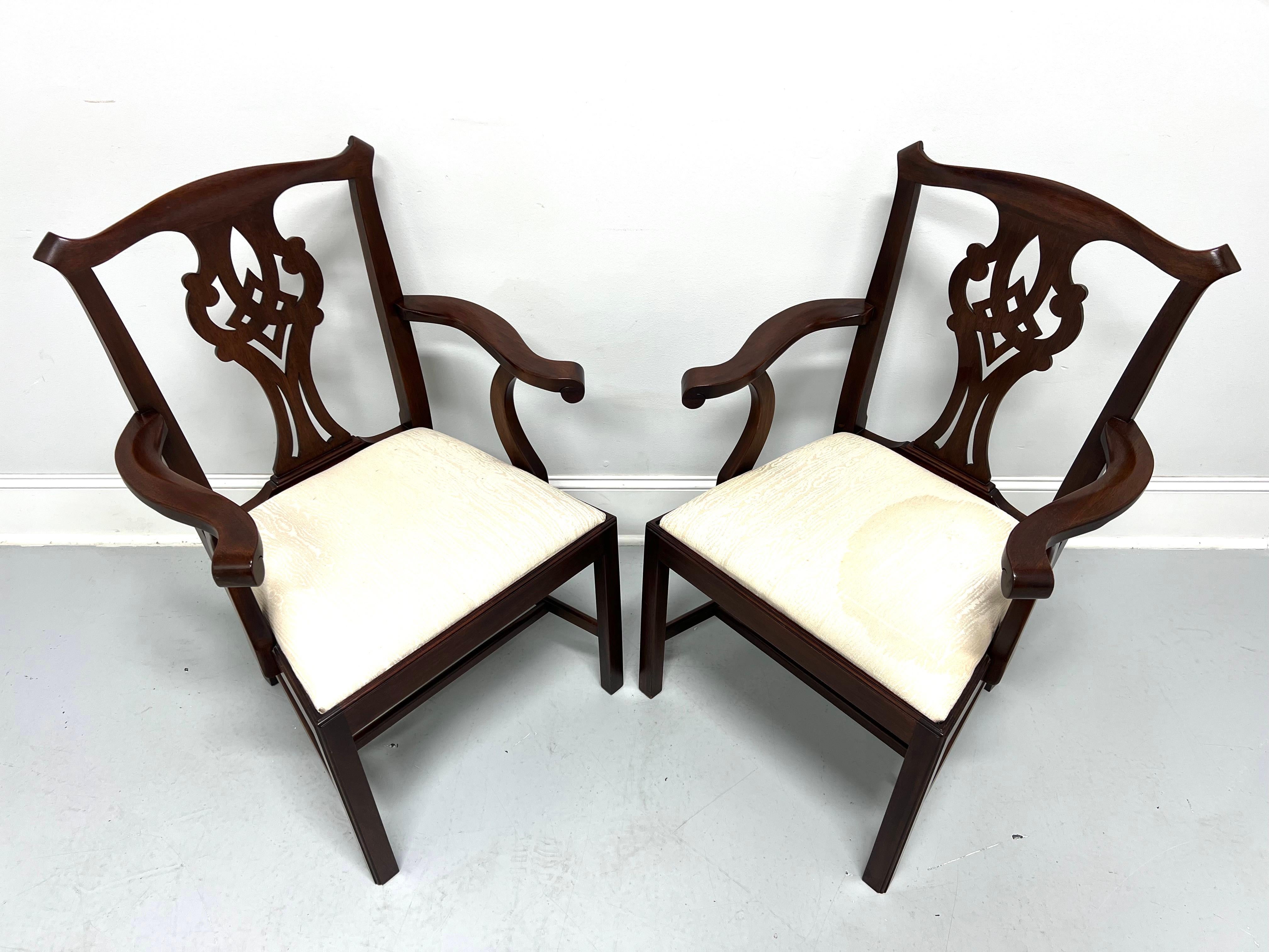 A pair of Chippendale style dining armchairs by Henkel Harris, of Winchester, Virginia, USA. Solid mahogany, carved crest rail & backrest, carved curved arms with arced supports, neutral cream color silk fabric upholstered seat, straight legs, and