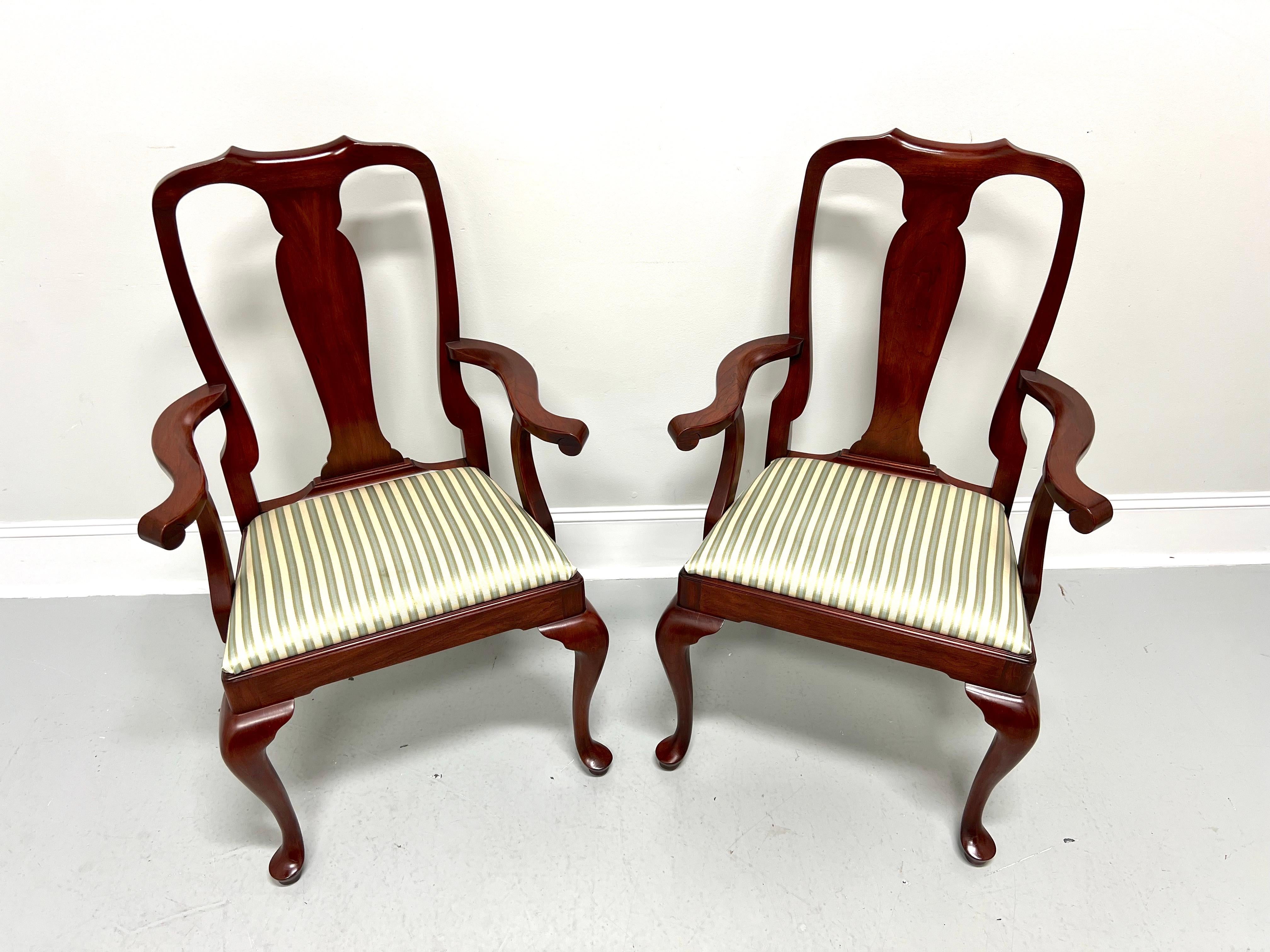 A pair of Queen Anne style dining armchairs by Henkel Harris, of Winchester, Virginia, USA. Solid wild black cherry wood, carved center backrest, carved curved arms with curved supports, upholstered seat in a multi-color stripe patterned fabric,